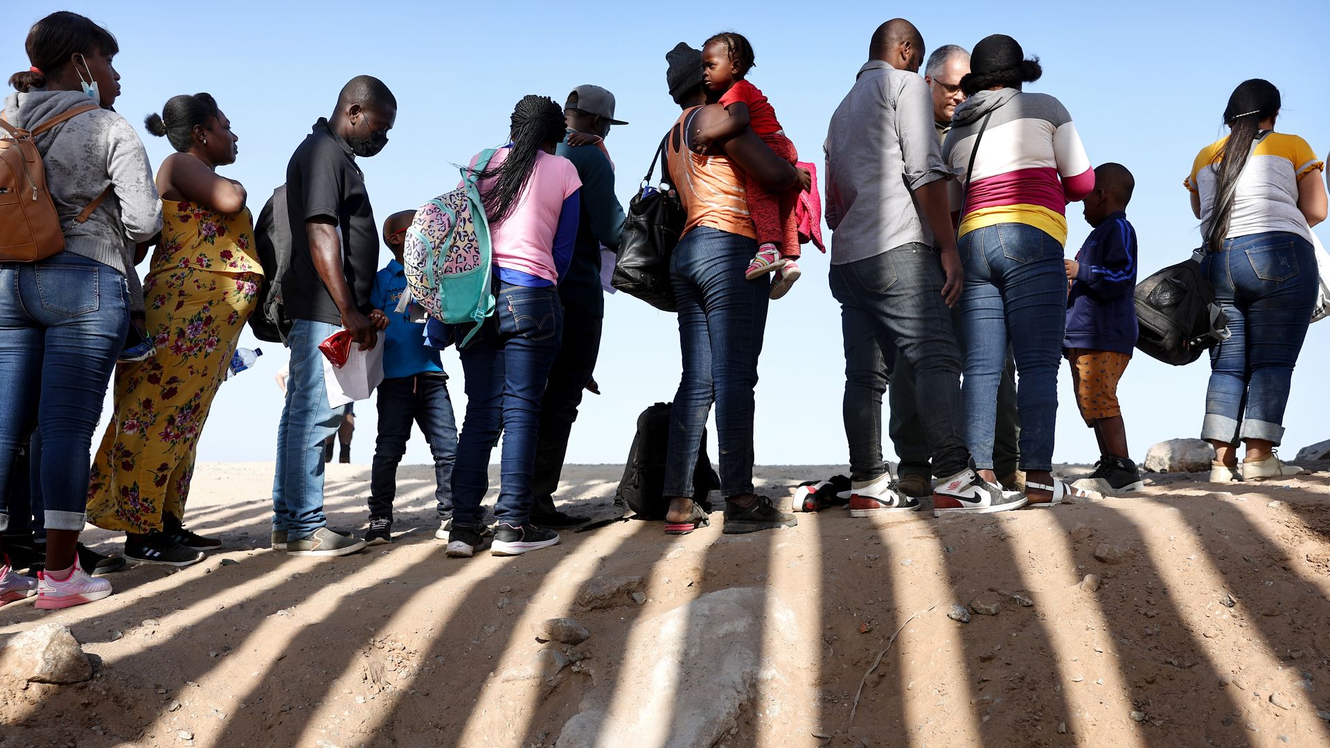 Immigrants from Haiti, who crossed through a gap in the U.S.-Mexico border barrier, wait in line to be processed by the U.S. Border Patrol on May 20, 2022 in Yuma, Arizona. Title 42, the controversial pandemic-era border policy enacted by former President Trump, which cites COVID-19 as the reason to