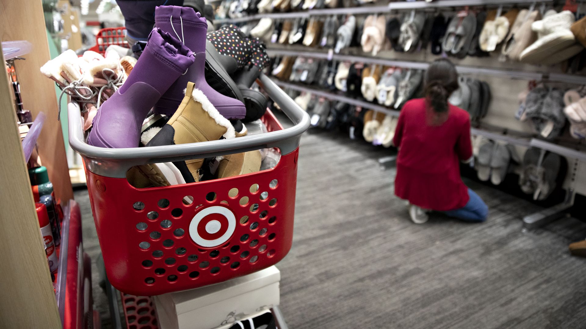 Photo of a Target employee crouching in an aisle while a cart filled with shoes is nearby