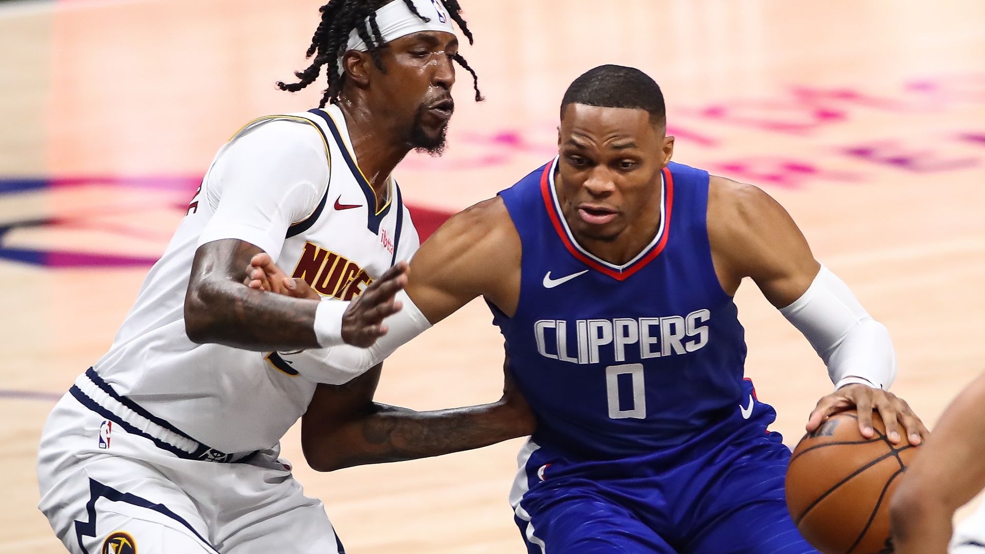 Two men run against each other while one man holds an orange basketball while attempting to move forward. 
