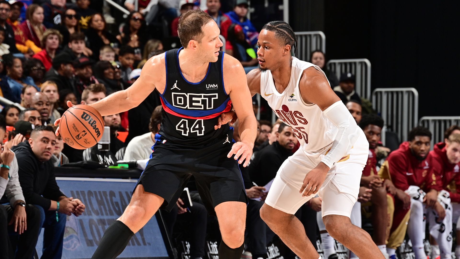 The Pistons' Bojan Bogdanovic (in black) dribbles against the Cavs' Isaac Okoro (in white)