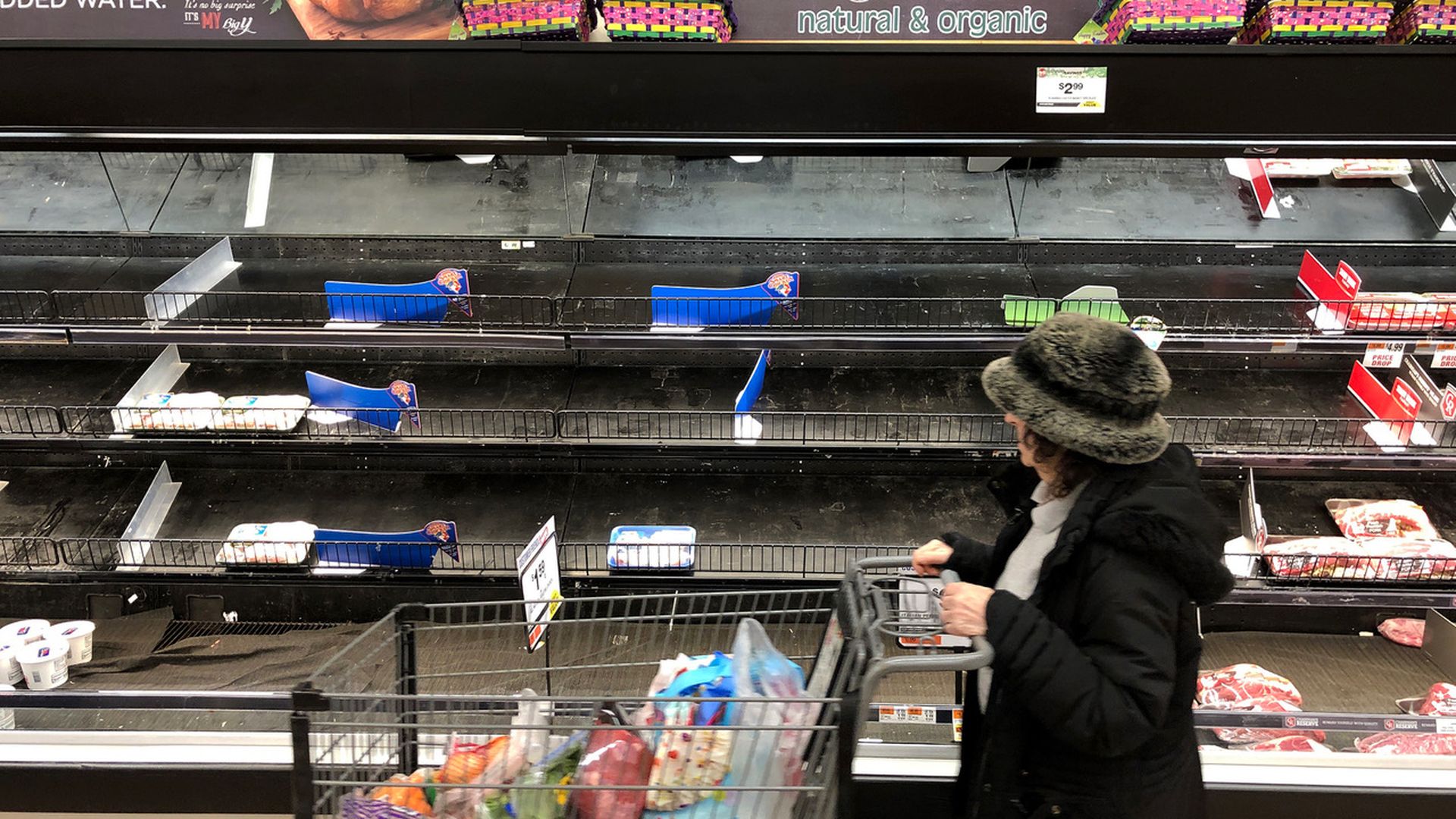Meat section of a grocery store is mostly empty.