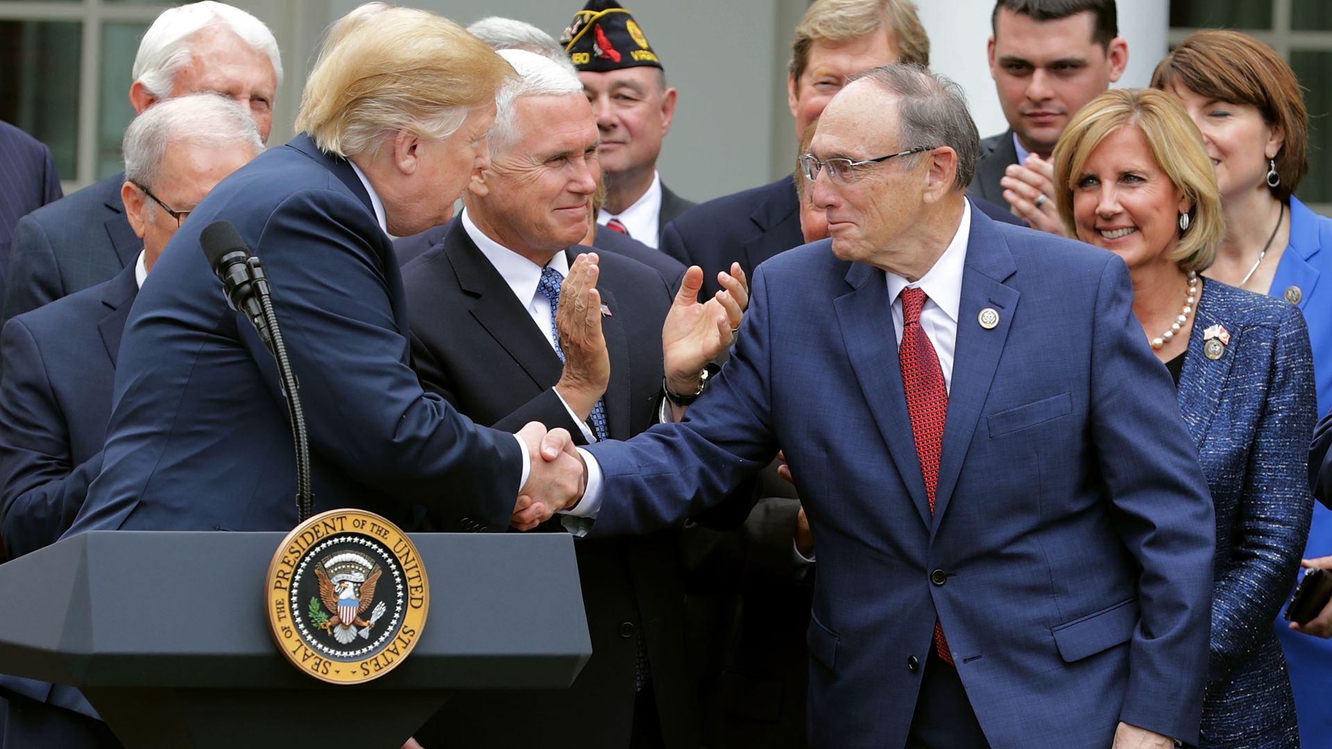 Phil Roe shakes Donald Trump's hand at a podium. 