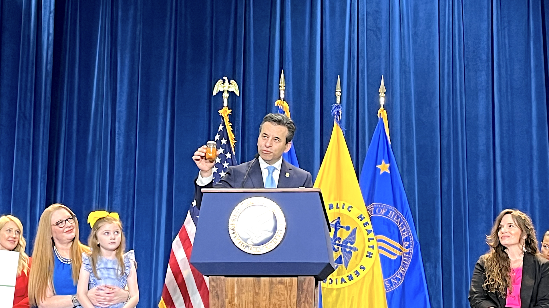 FDA Commissioner Marty Makary holds up a bottle with an orange liquid to show the kind of colors a natural food dye can produce.