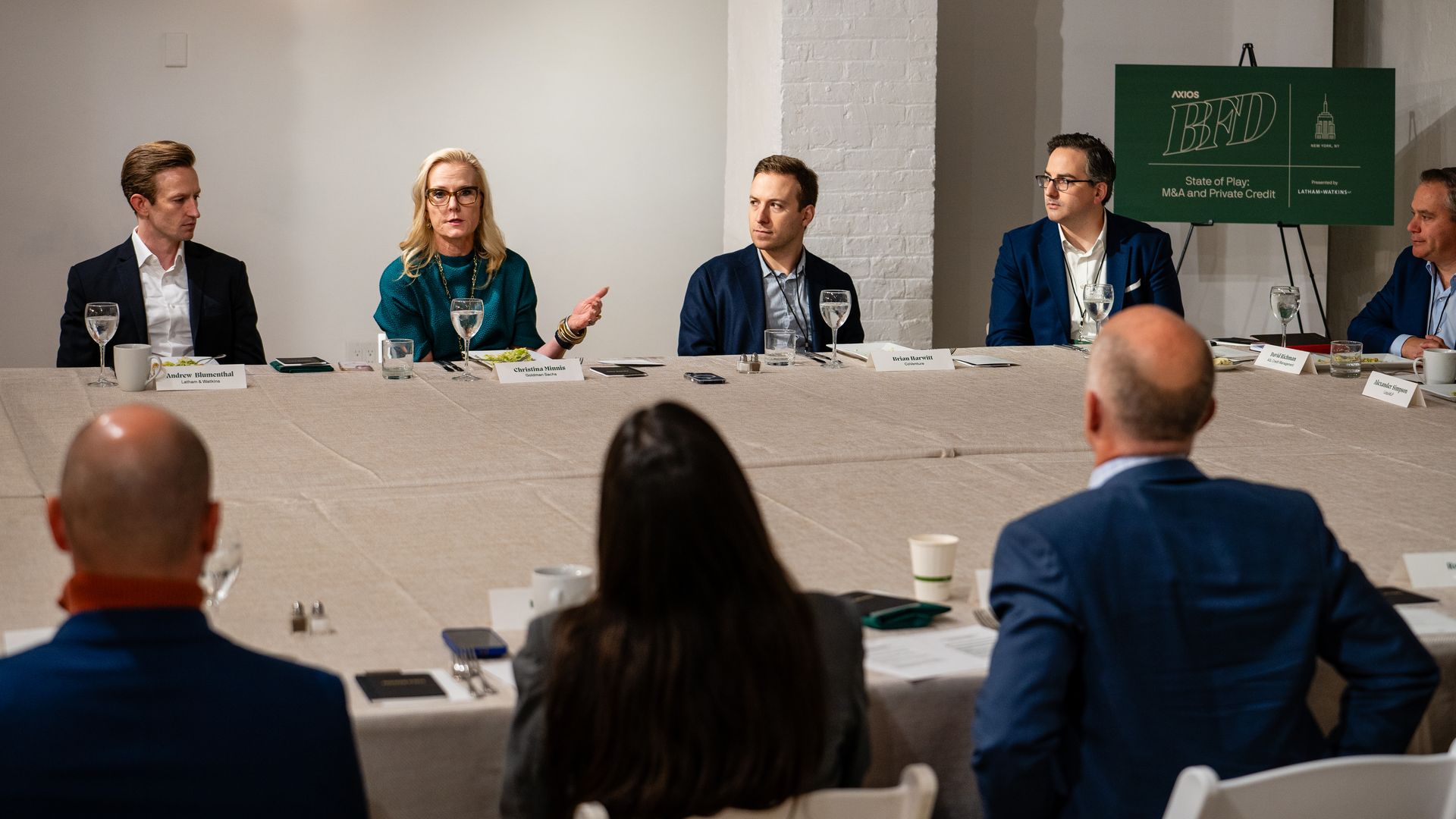People seated around a table with a green sign in the back that says BFD