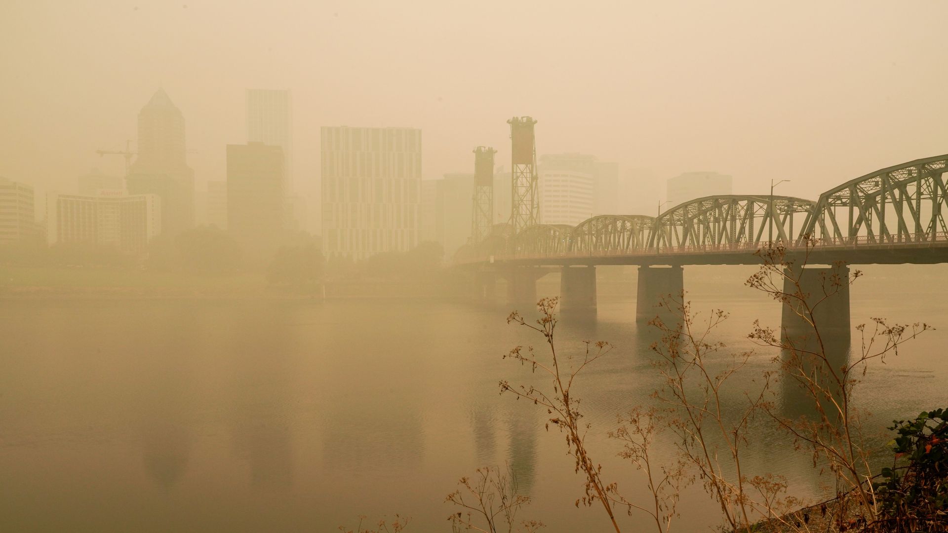 A photo of the downtown Portland riverfront with hazy, orange-hued skies from nearby wildfires.
