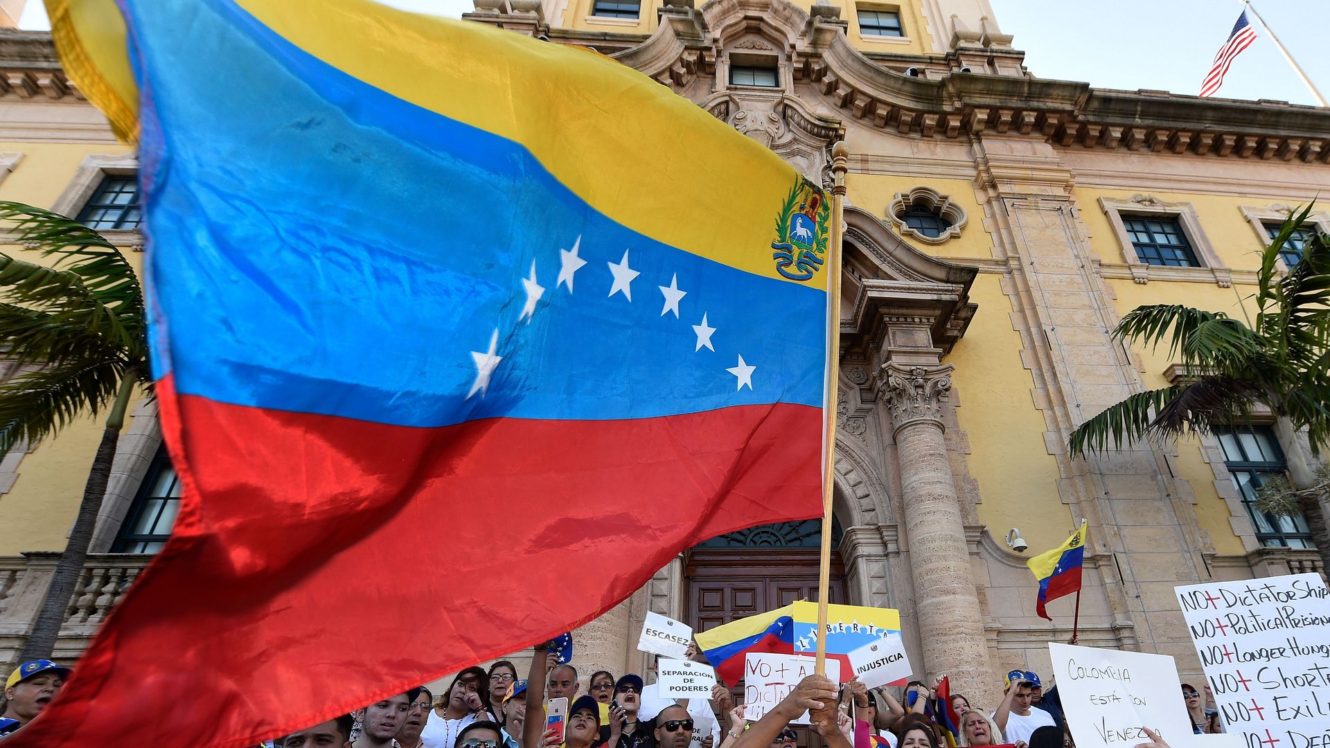 A Venezuelan flag waves above a crowd of protestors in Miami.