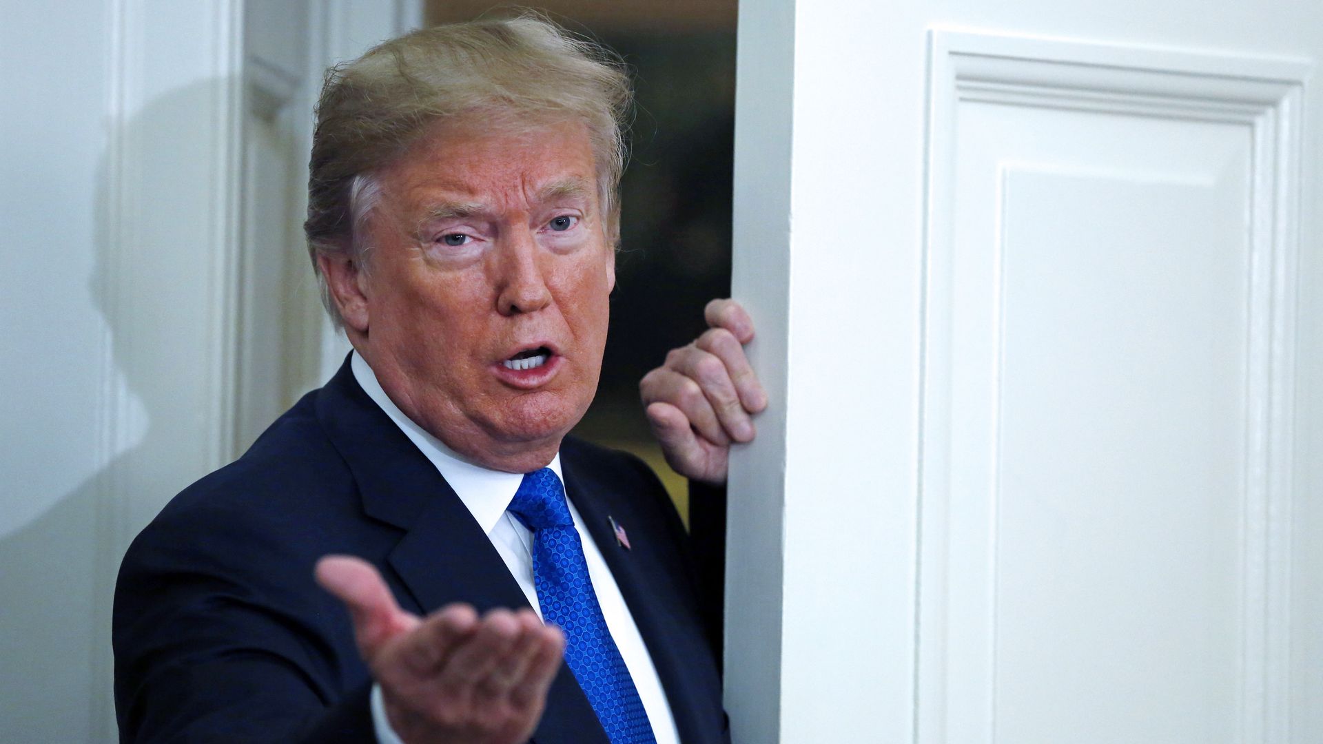 Donald Trump exiting a room with his right hand held out and talking 