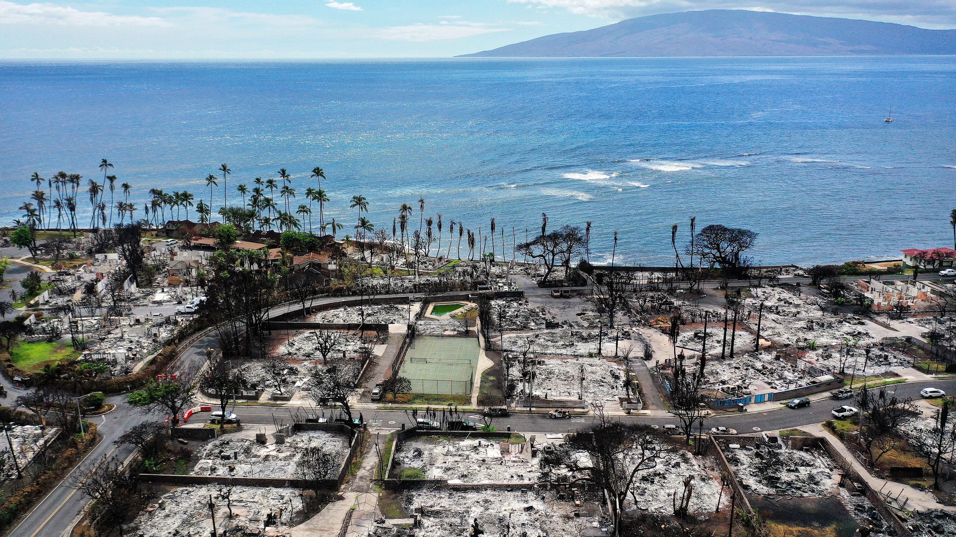 In an aerial view, a recovery vehicle drives past burned structures and cars two months after a devastating wildfire on October 09, 2023 in Lahaina, Hawaii. 