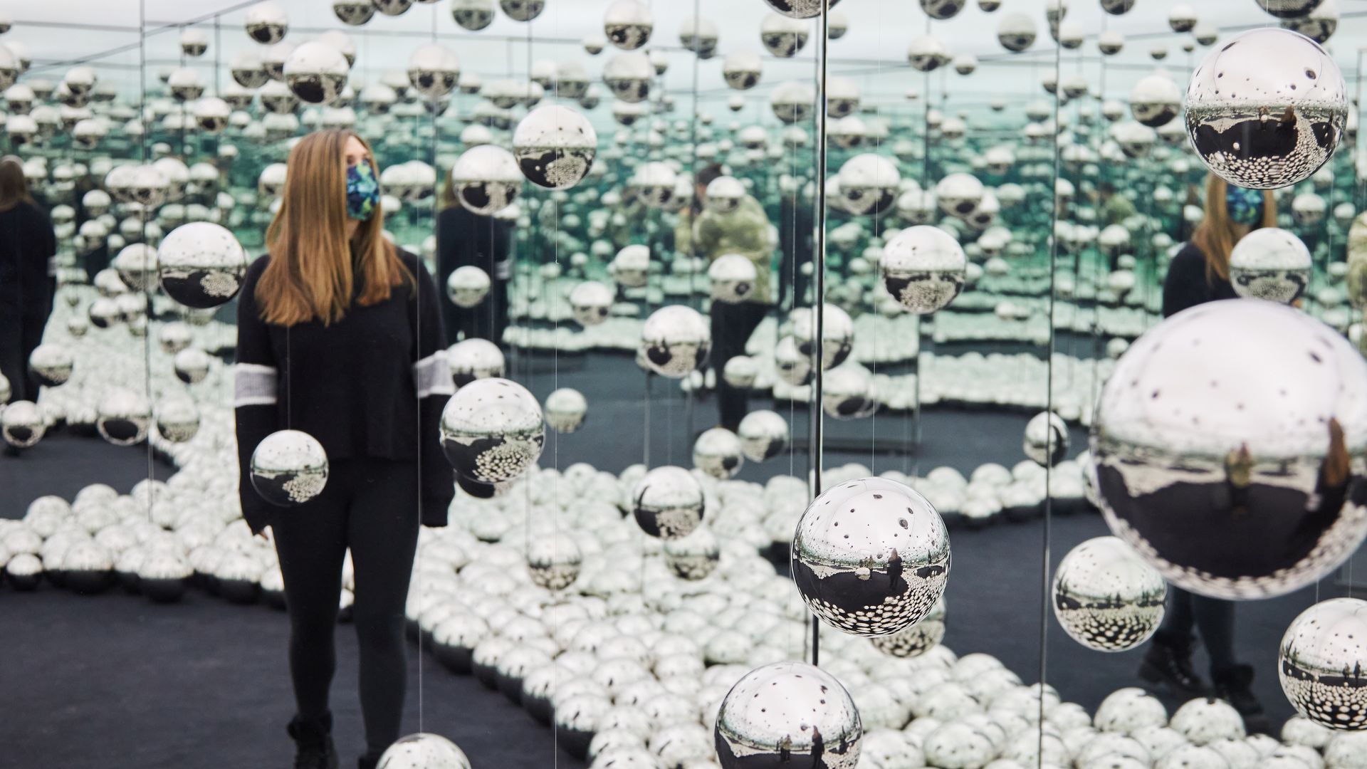 A visitor to the WNDR Museum in Chicago immerses herself in an art exhibit of mirrors.