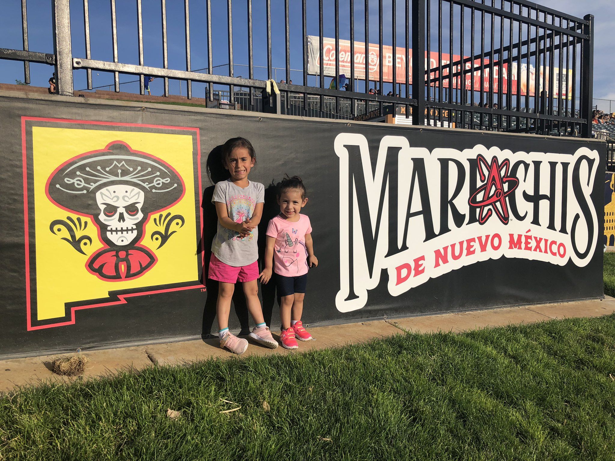 Two girls stand in fron the Mariachis de Nuevo México logo in Albuquerque, N.M.