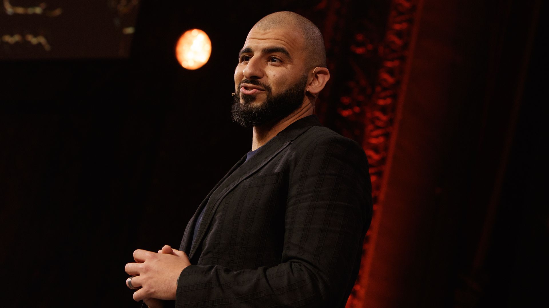 Photo of a man in a sports jacket speaking on stage 