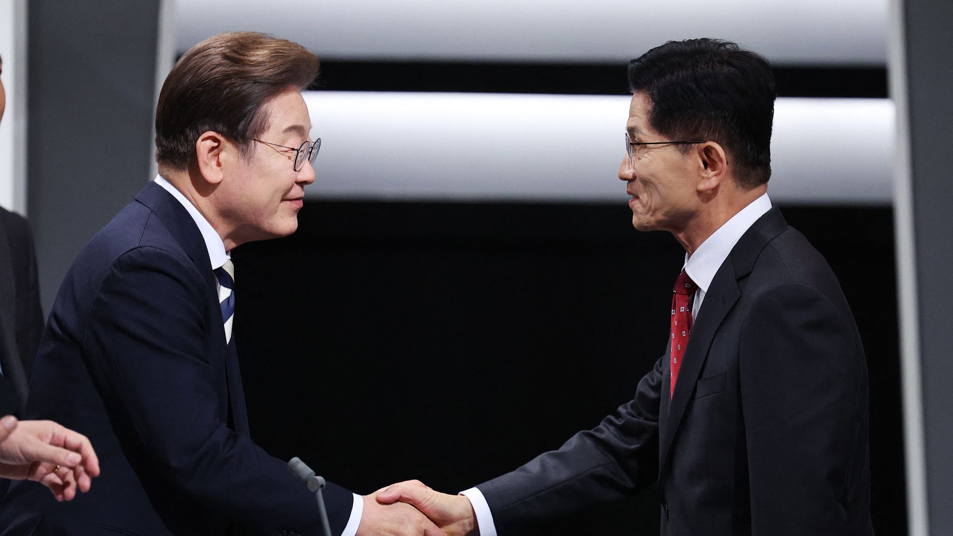 South Korean presidential candidates Kim Moon-soo and Lee Jae-myung shake hands before a debate.