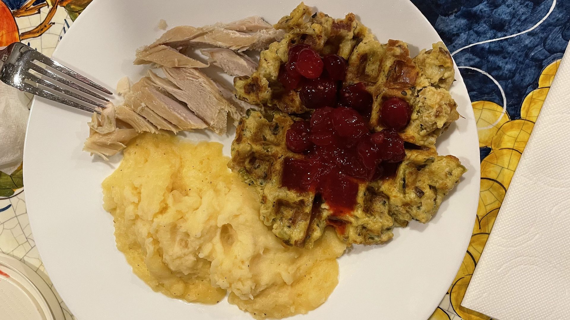 A stuffle covered in cranberry sauce next to turkey and mashed potatoes on a plate