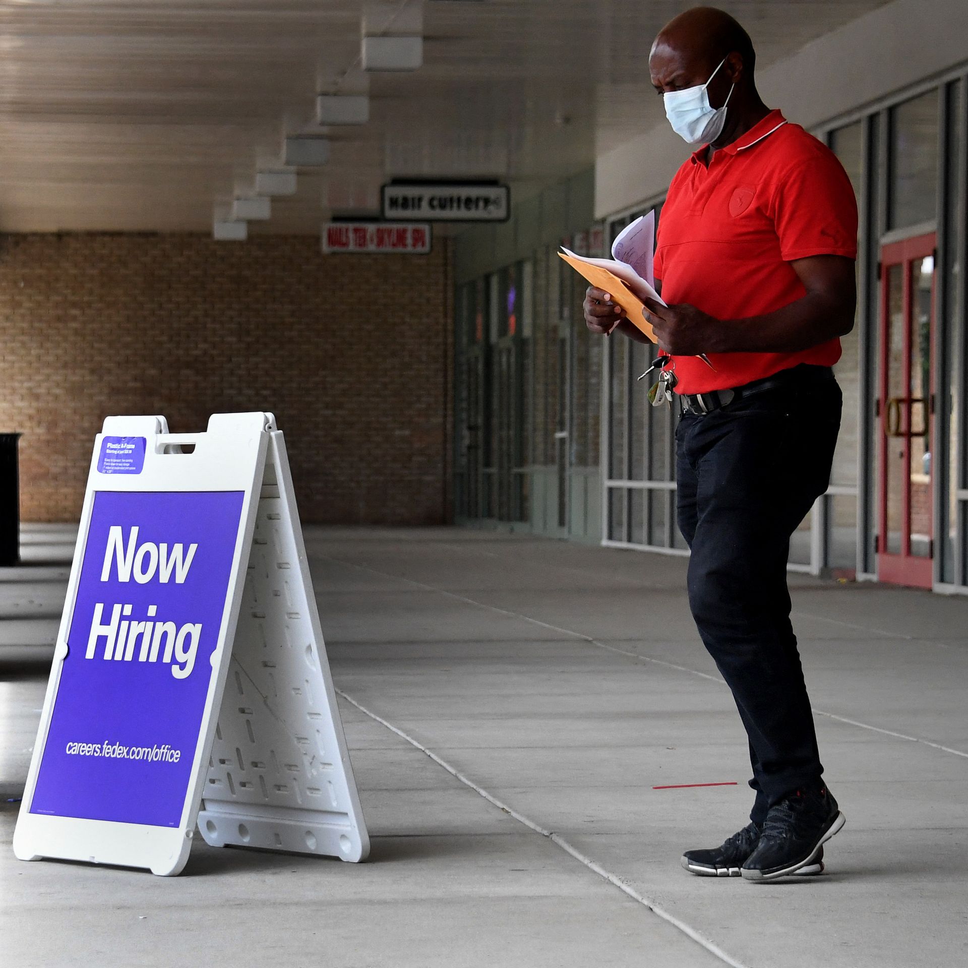 A man walks by a "Now Hiring" sign outside a store in Arlington, Va.