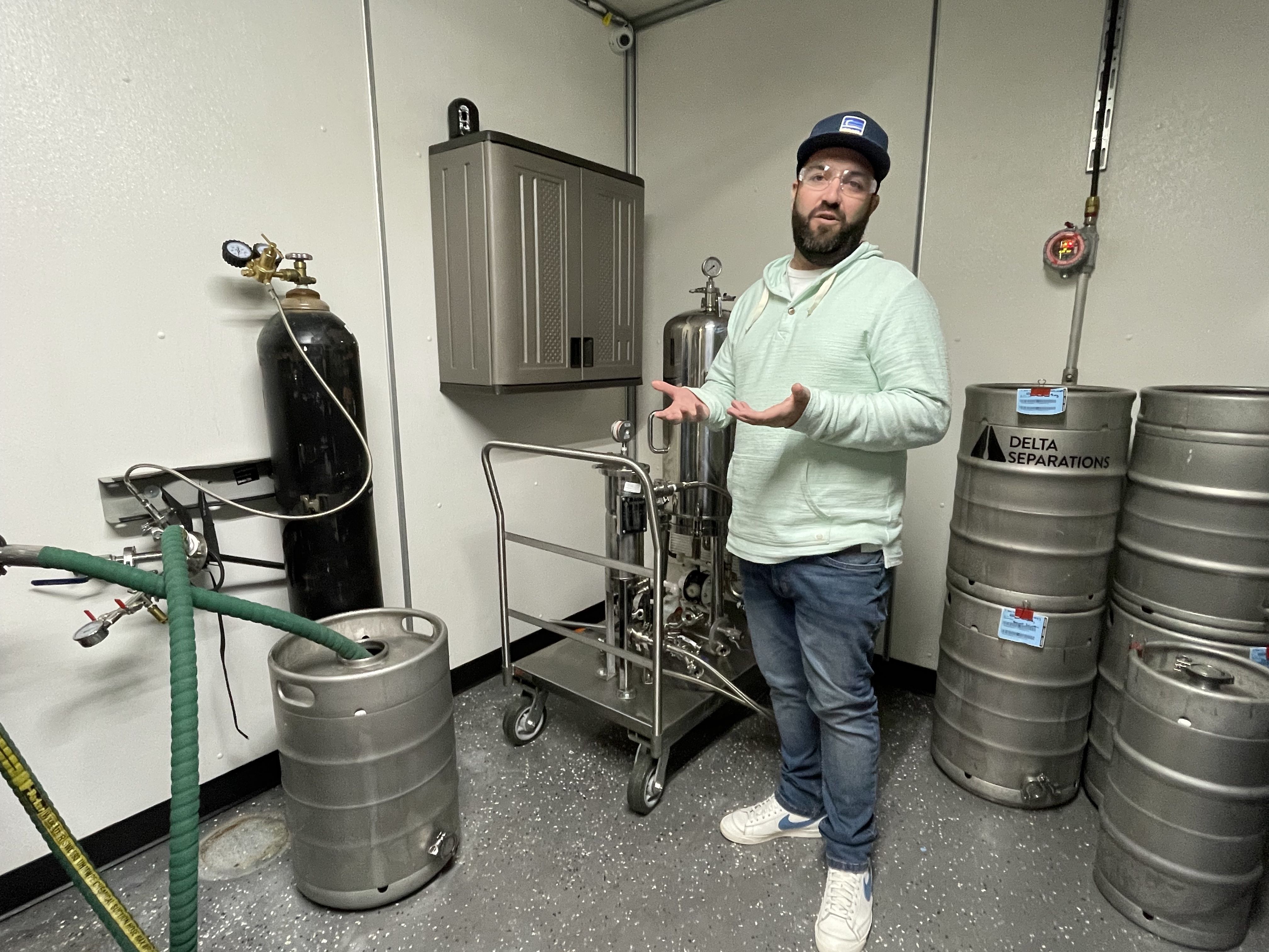 Coast Cannabis co-founder Brian Cusnick stands in front of several barrels where cannabis flower is distilled into cannabis oil.