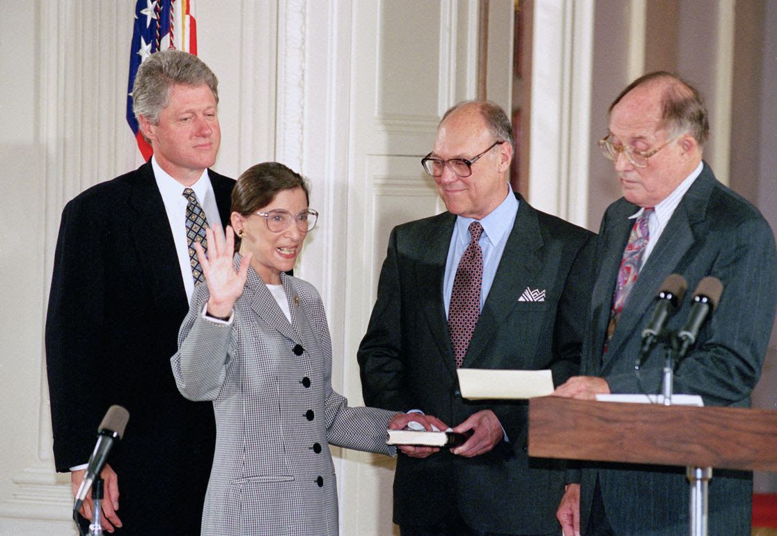 On Aug. 10, 1993, Ruth Bader Ginsburg takes the oath from Chief Justice William Rehnquist (right) during an East Room ceremony with President Clinton.  Ginsburg's late husband, Martin holds the Bible.