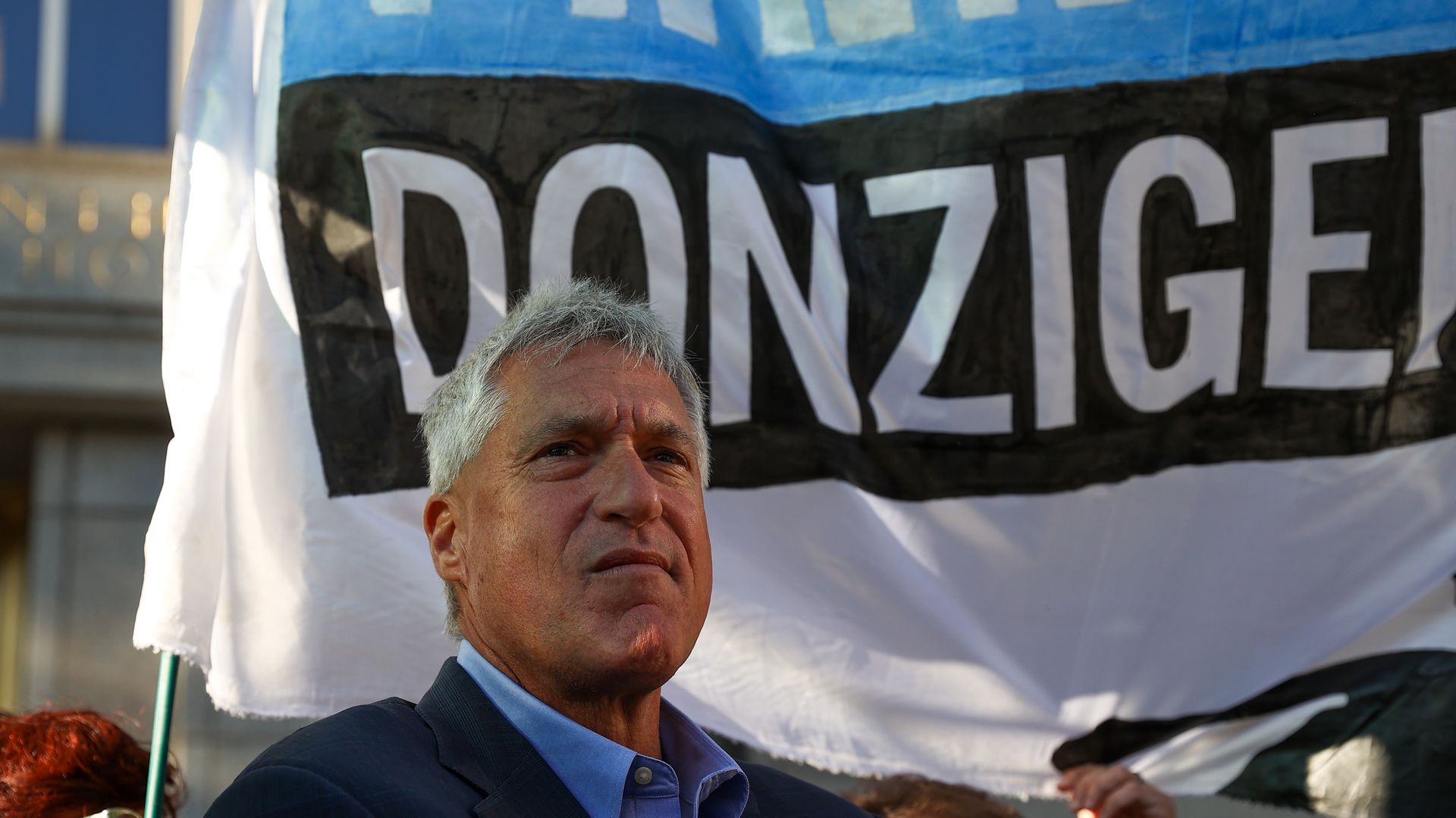 Photo of Steven Donziger's face next to a giant "Free Donziger" sign