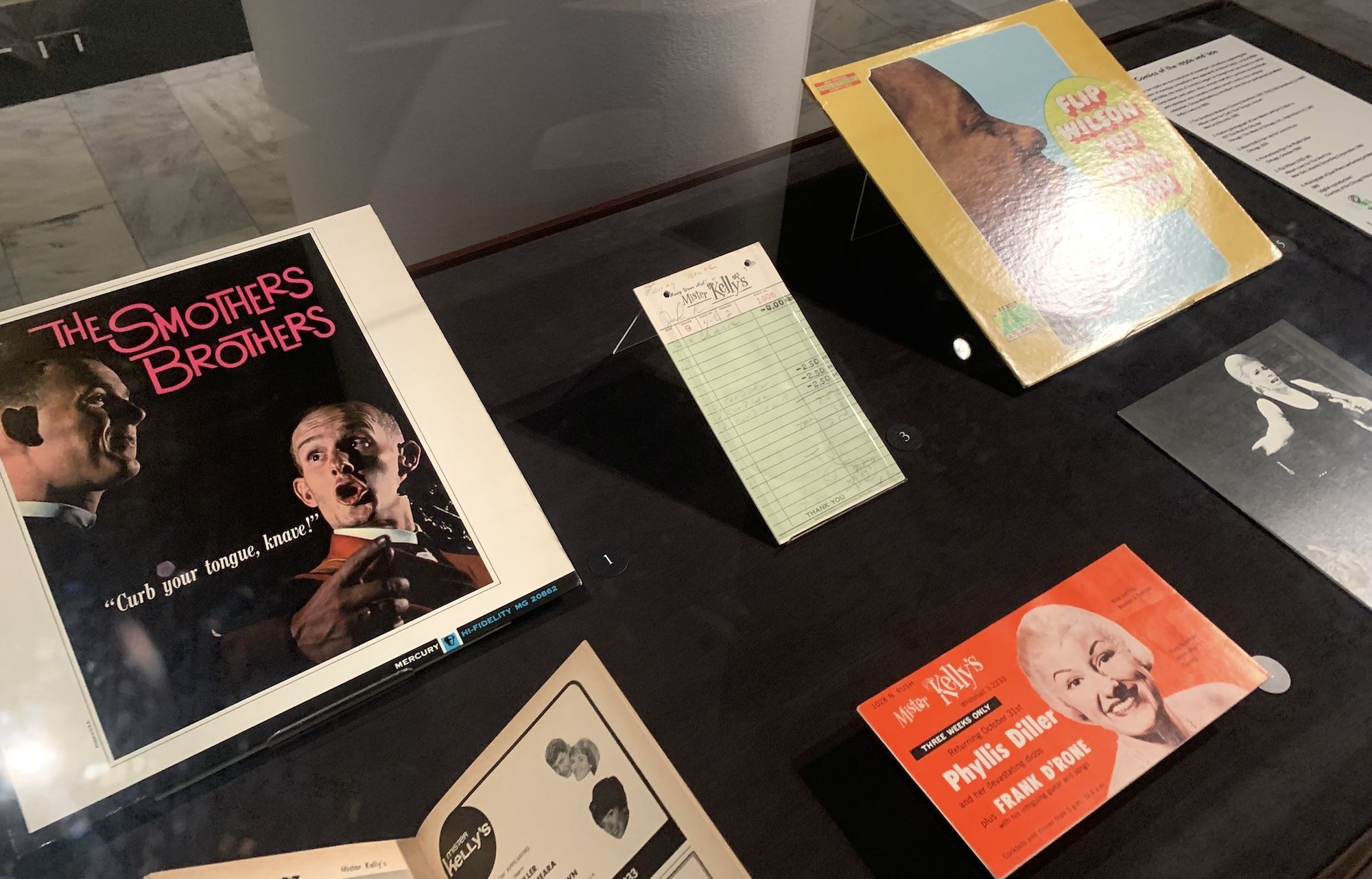 album cover, old diner receipt, postcard in glass case.