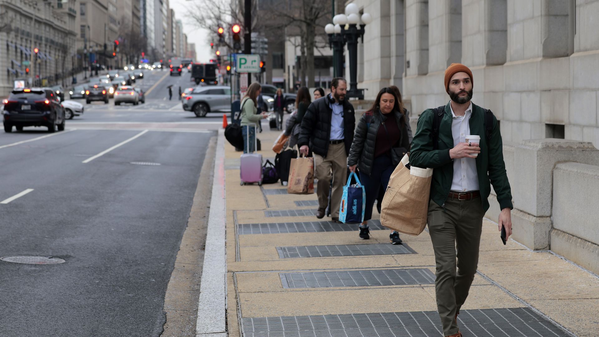 Former USAID employees carry their belongings in bags as they depart USAID headquarters.