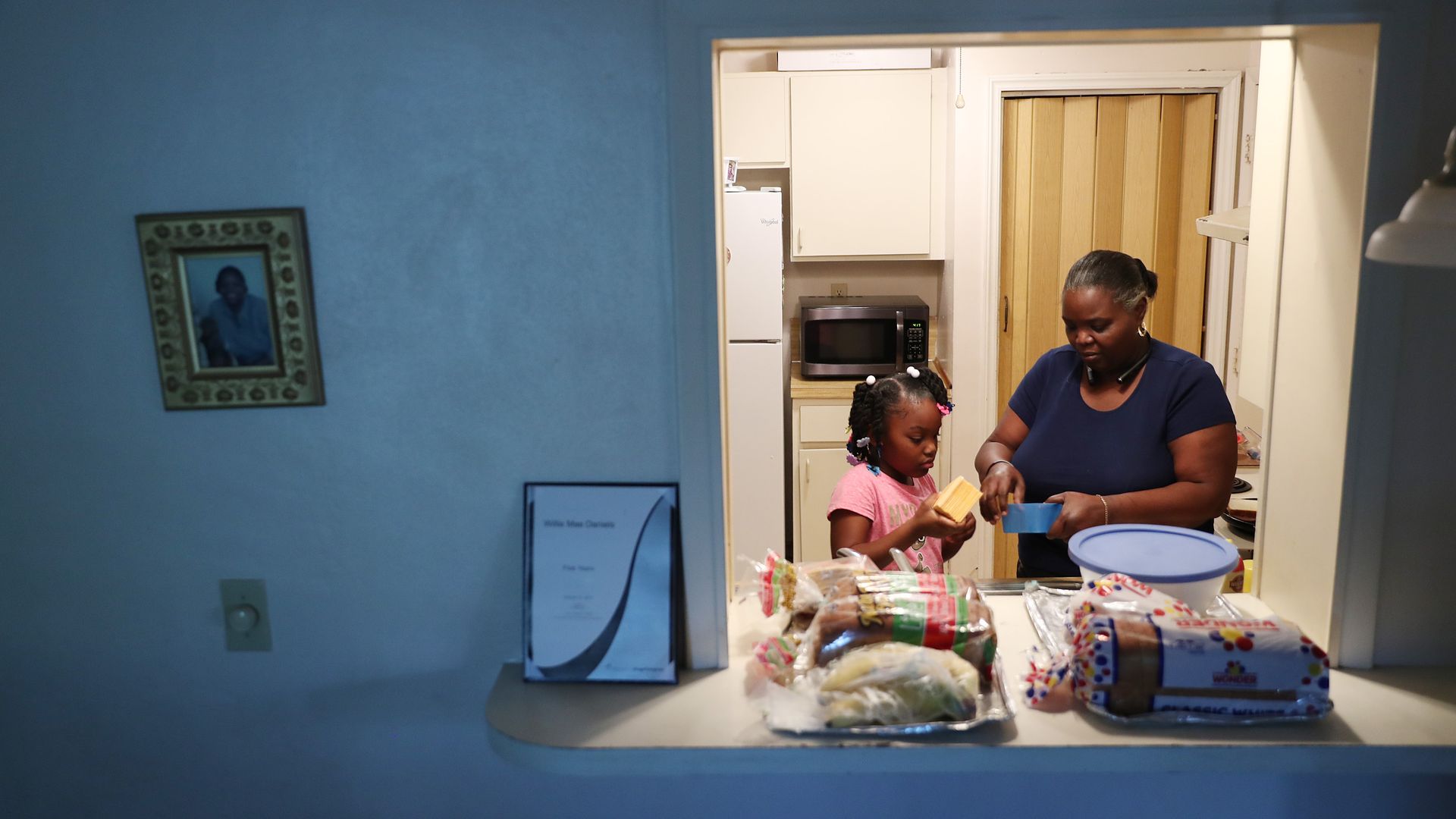 A woman and her granddaughter prepare food in a kitchen.