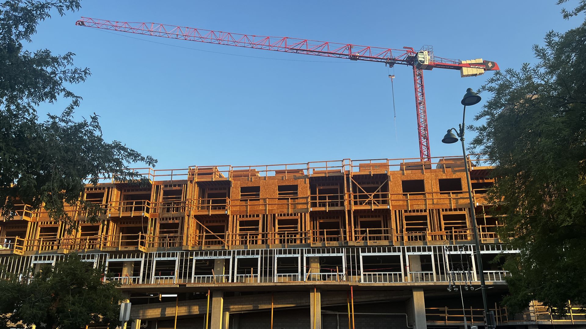 A Crane next to scaffolding on a multi-story building.