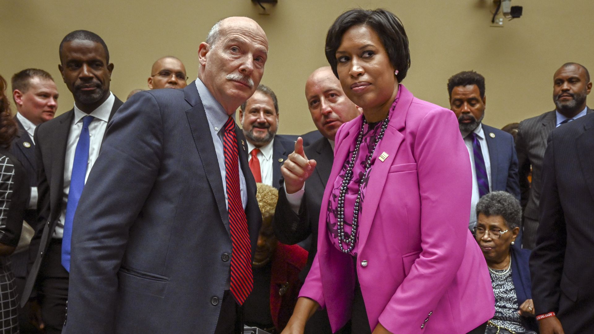 Phil Mendelson, left, and Muriel Bowser stand up inside a hearing room