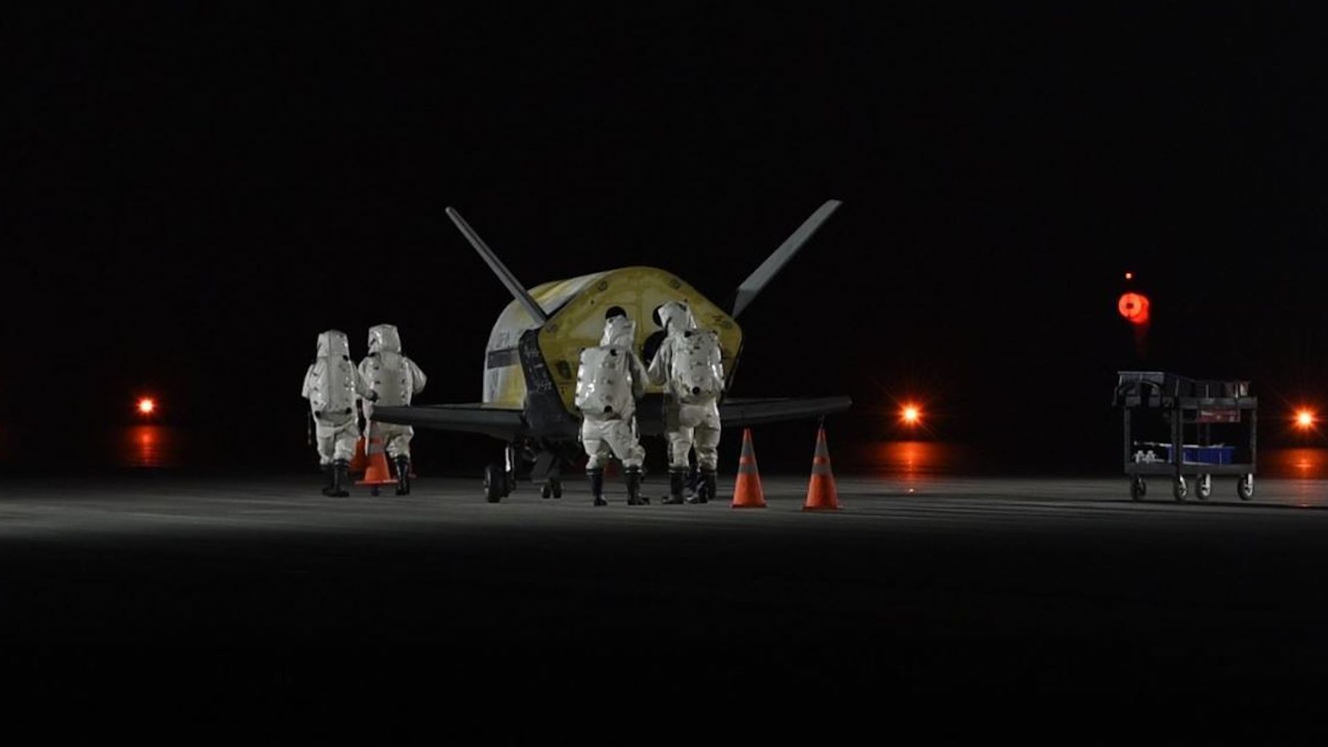 Workers tend to the X-37b space plane after landing in the dark in Florida