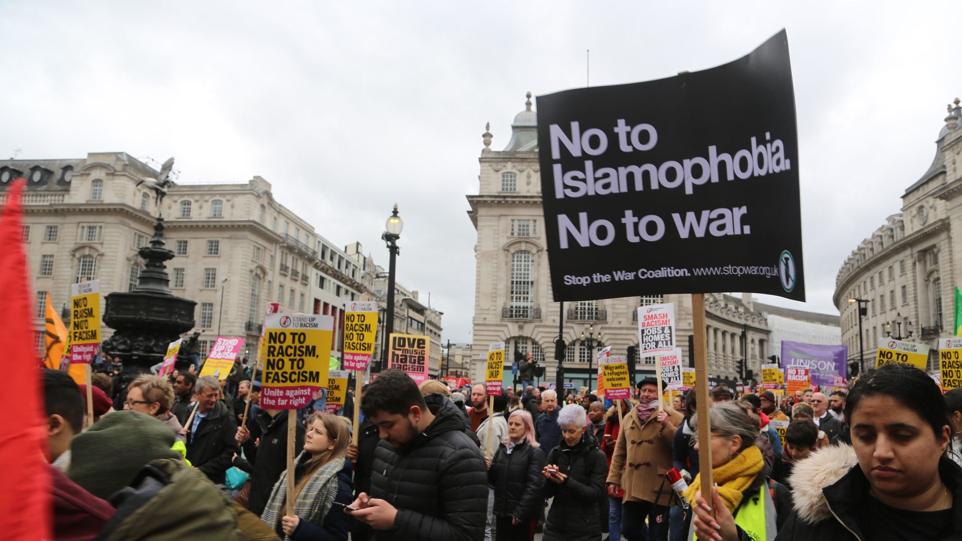 Protestors hold signs in a London square. The closest sign reads: "No to islamophobia. No to war."