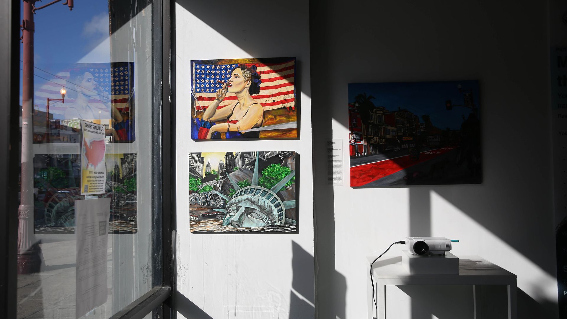 Photo of a wall displaying paintings next to a window