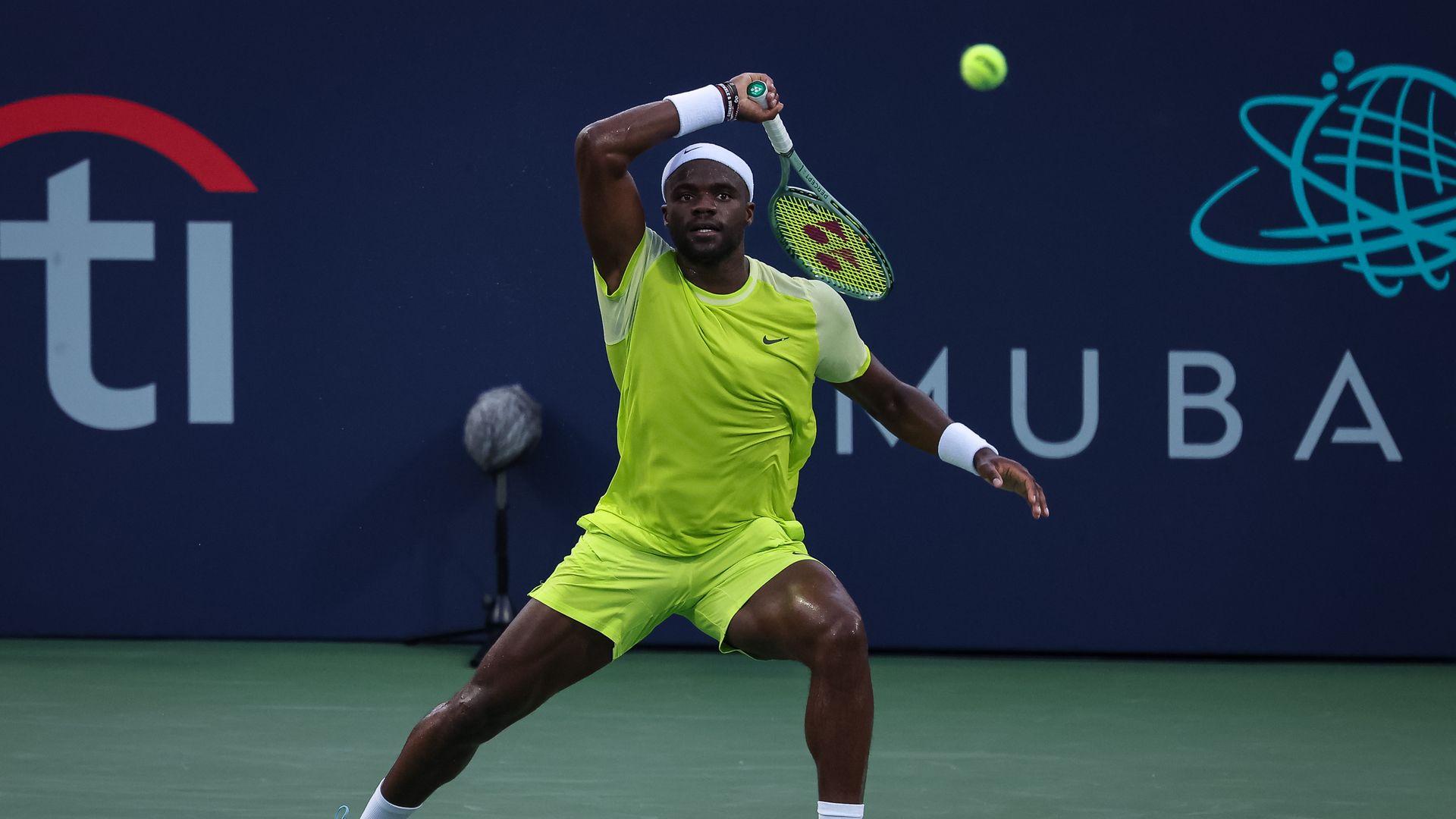 A photo of tennis player Frances Tiafoe hitting a tennis ball with a racquet. 
