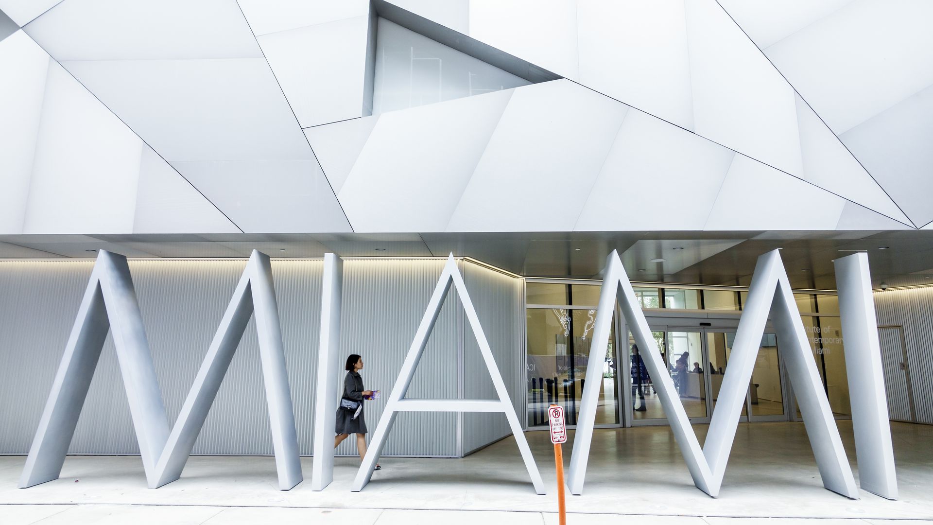 A woman walking in front of the entrance of the ICA in Miami. 