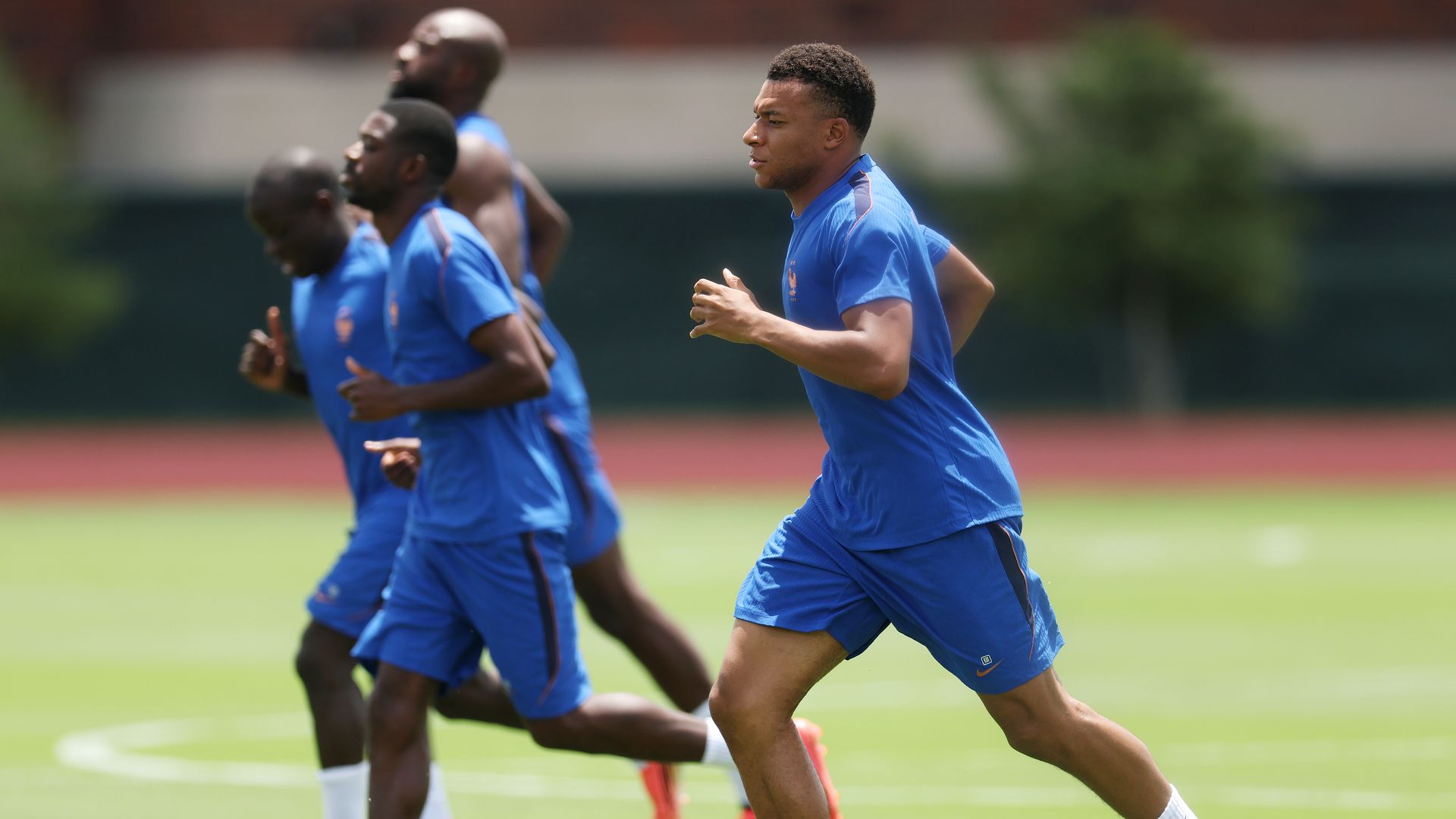 Kylian Mbappé and his teammates run drills on a field