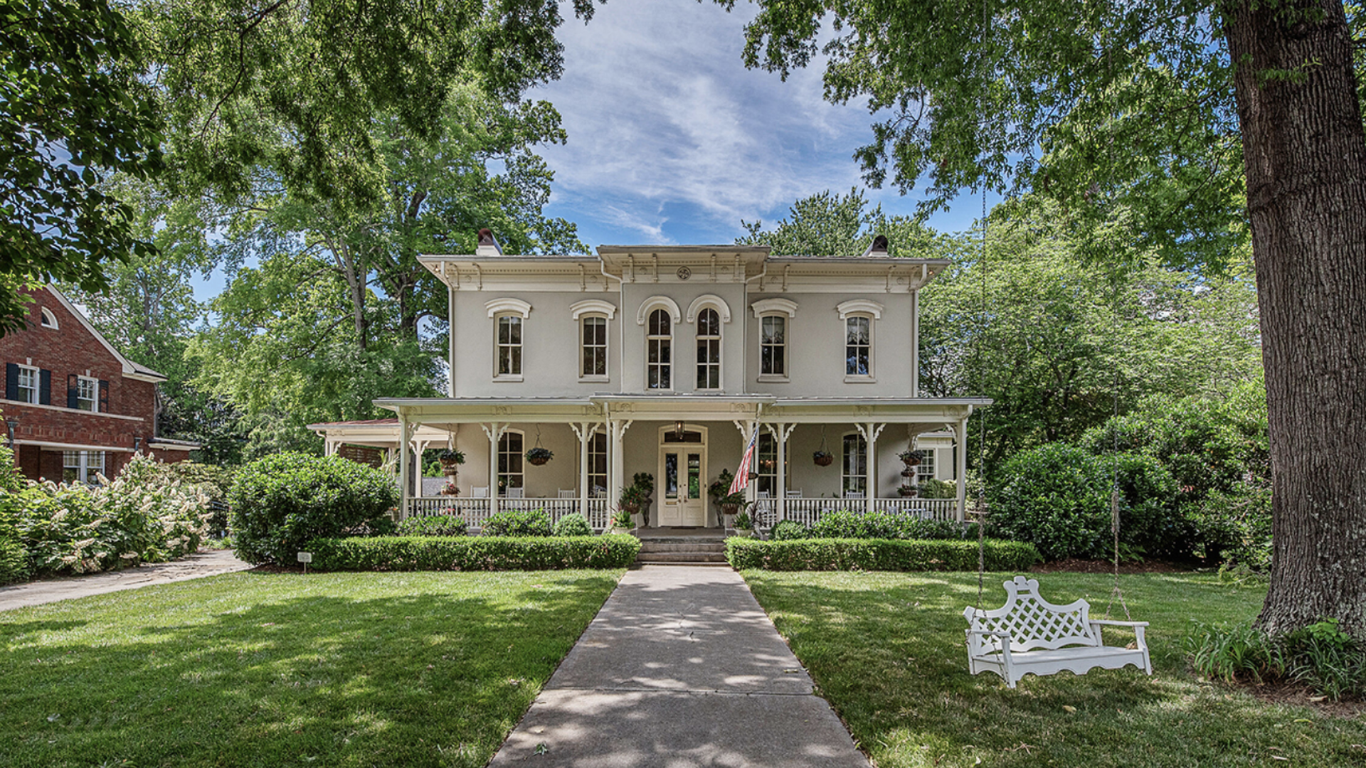 exterior of historic two story home with old oak trees shading the walkway