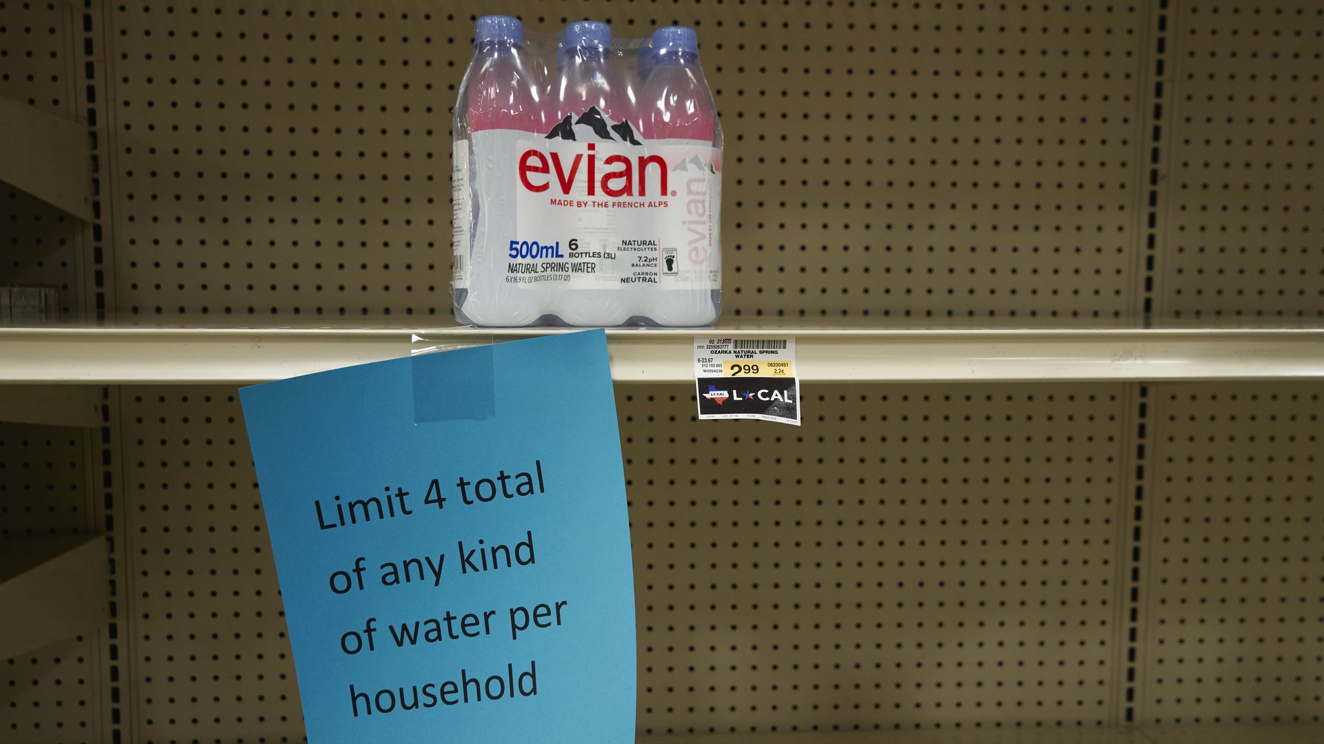 Picture of the last case of water bottles in front of a sign that reads: "limit 4 total of any kind of water per household."