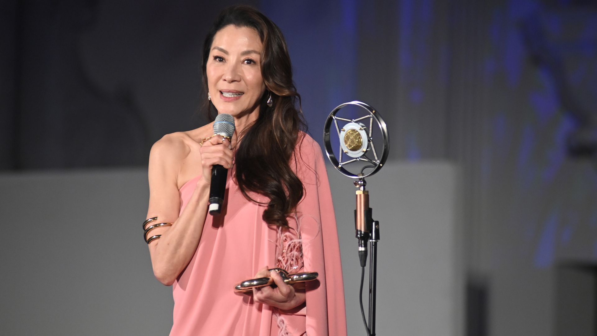 actress Michelle Yeoh on stage accepting award in pink dress