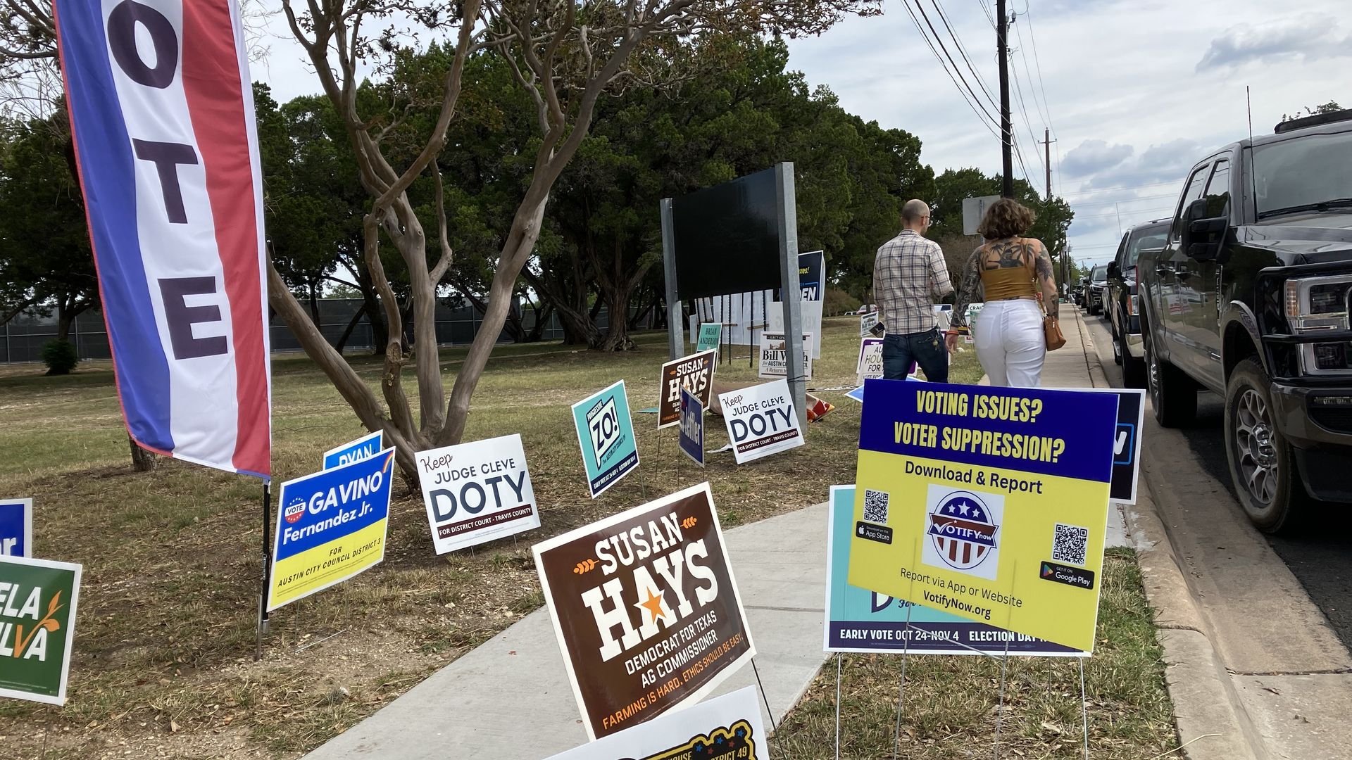 Signs about how to report voter suppression and candidate placards share space outside a South Austin polling site. Photo: Asher Price/Axios