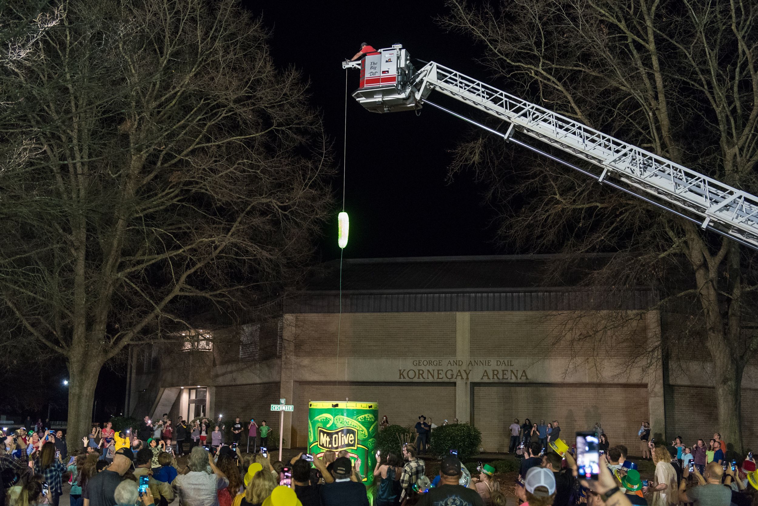a large pickle being dropped on a string into a Mount Olive jar 
