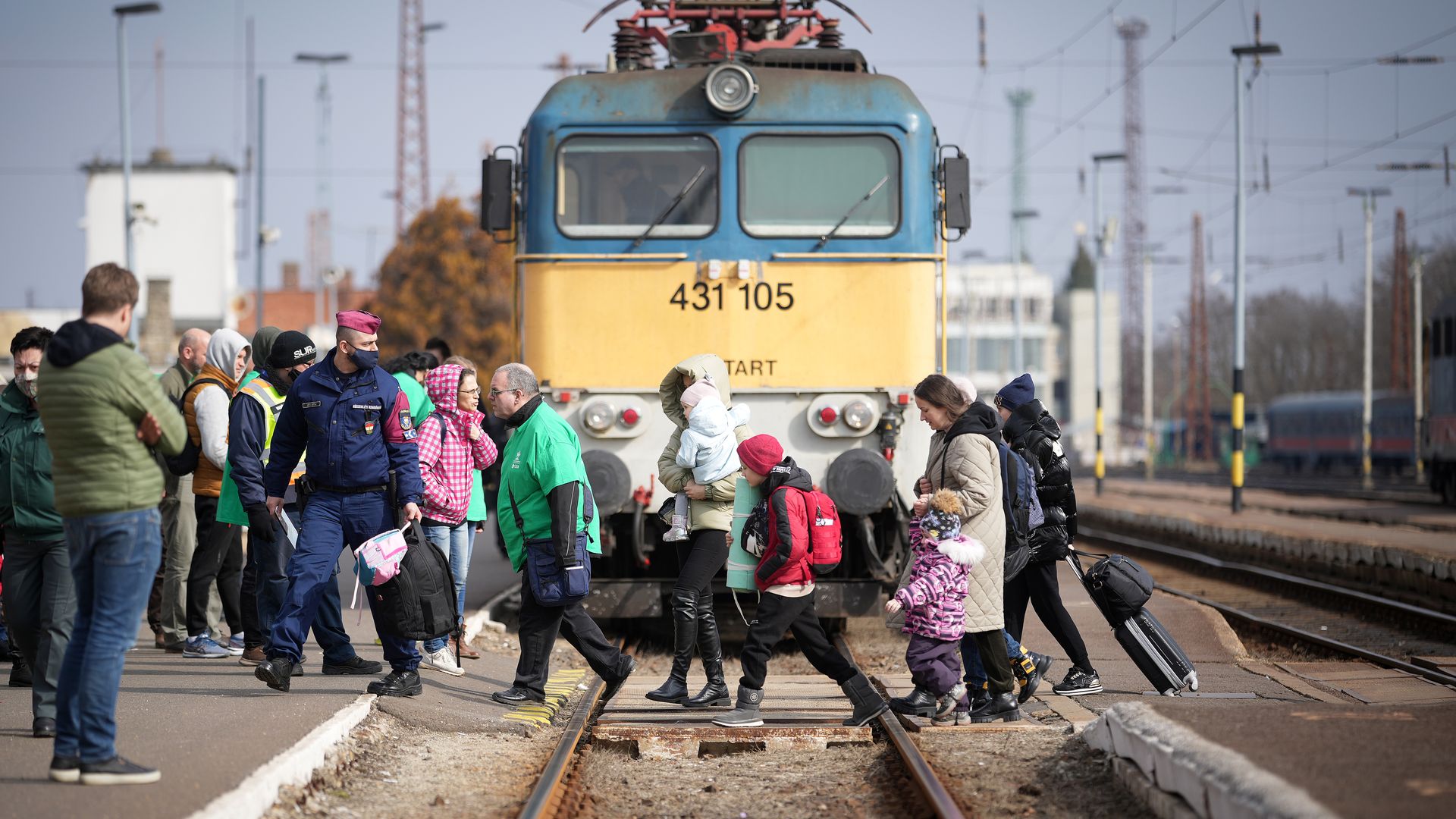 Picture of people crossing railroads in front of a train