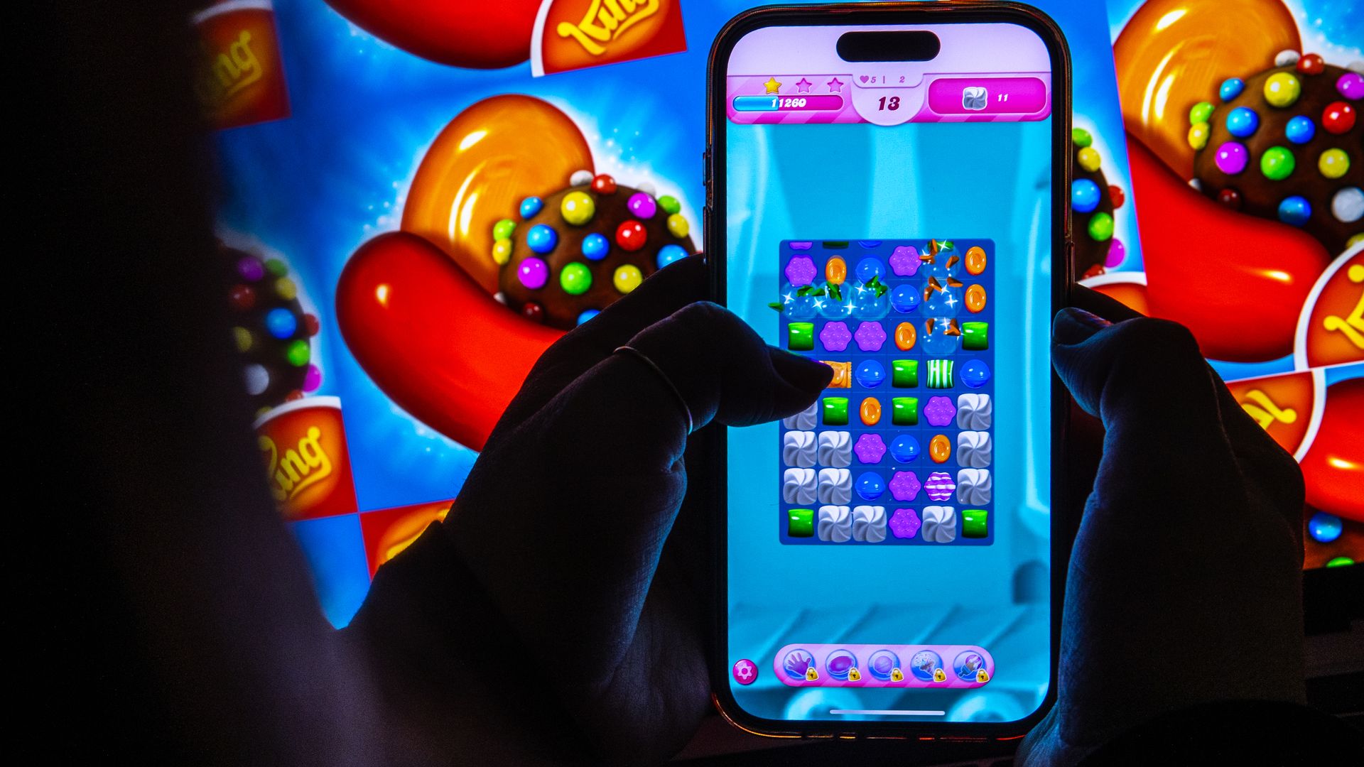A person holding a smartphone with the Candy Crush game open