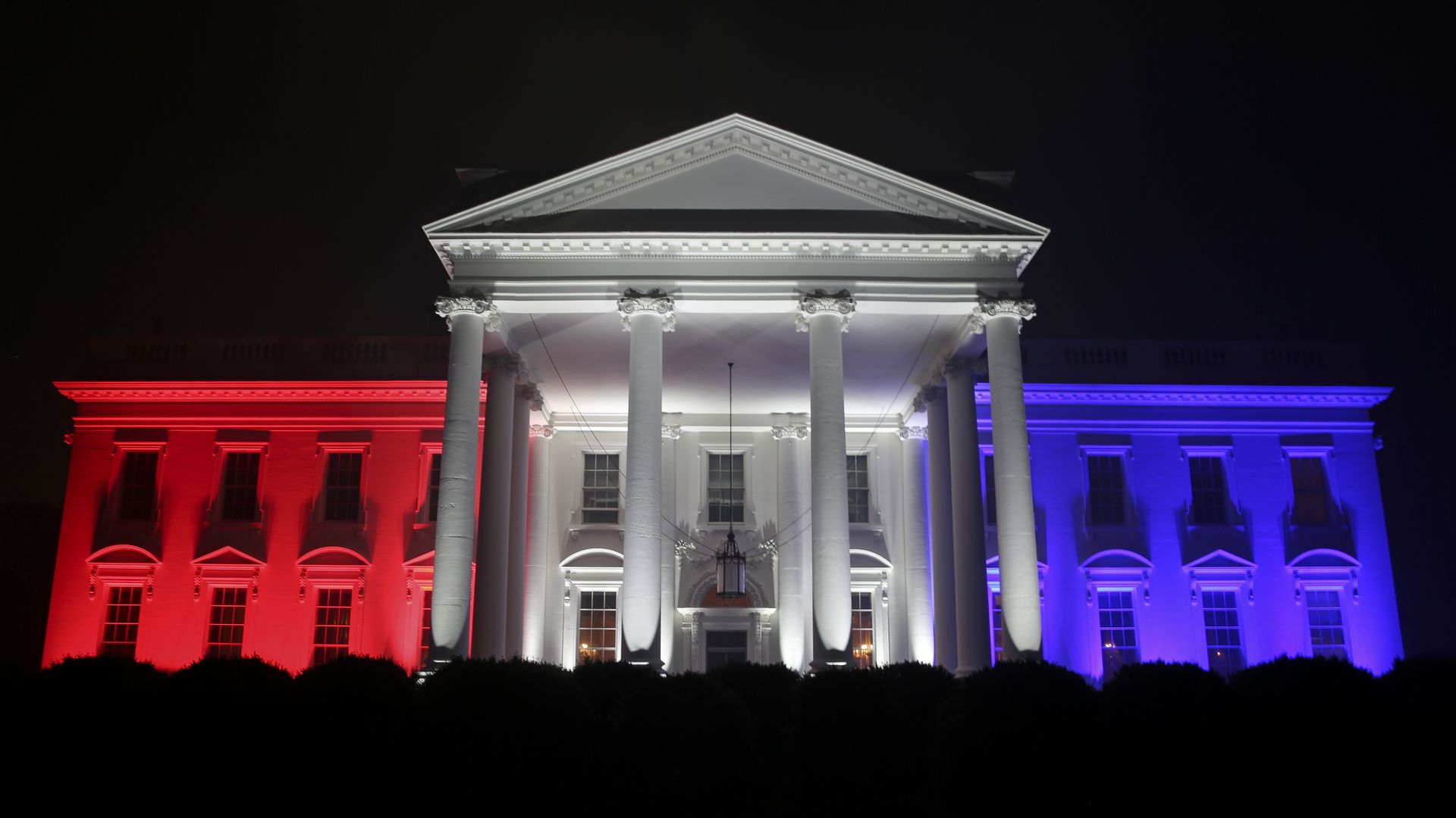 A photo of the White House bathed in Red, White and Blue light