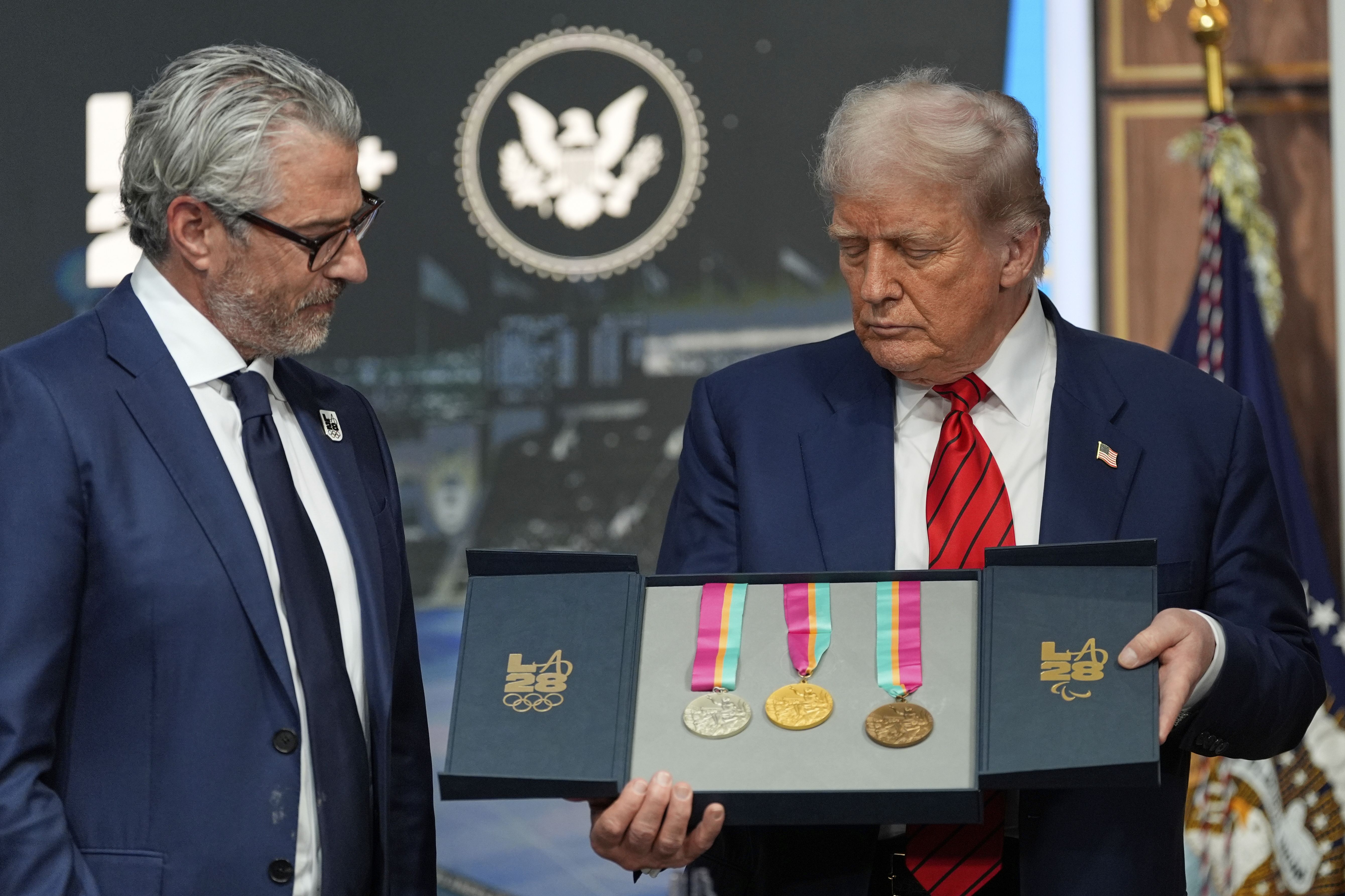 Casey Wasserman, chairman of LA28, presents President Trump with a full set of medals from the 1984 Olympics in Los Angeles.