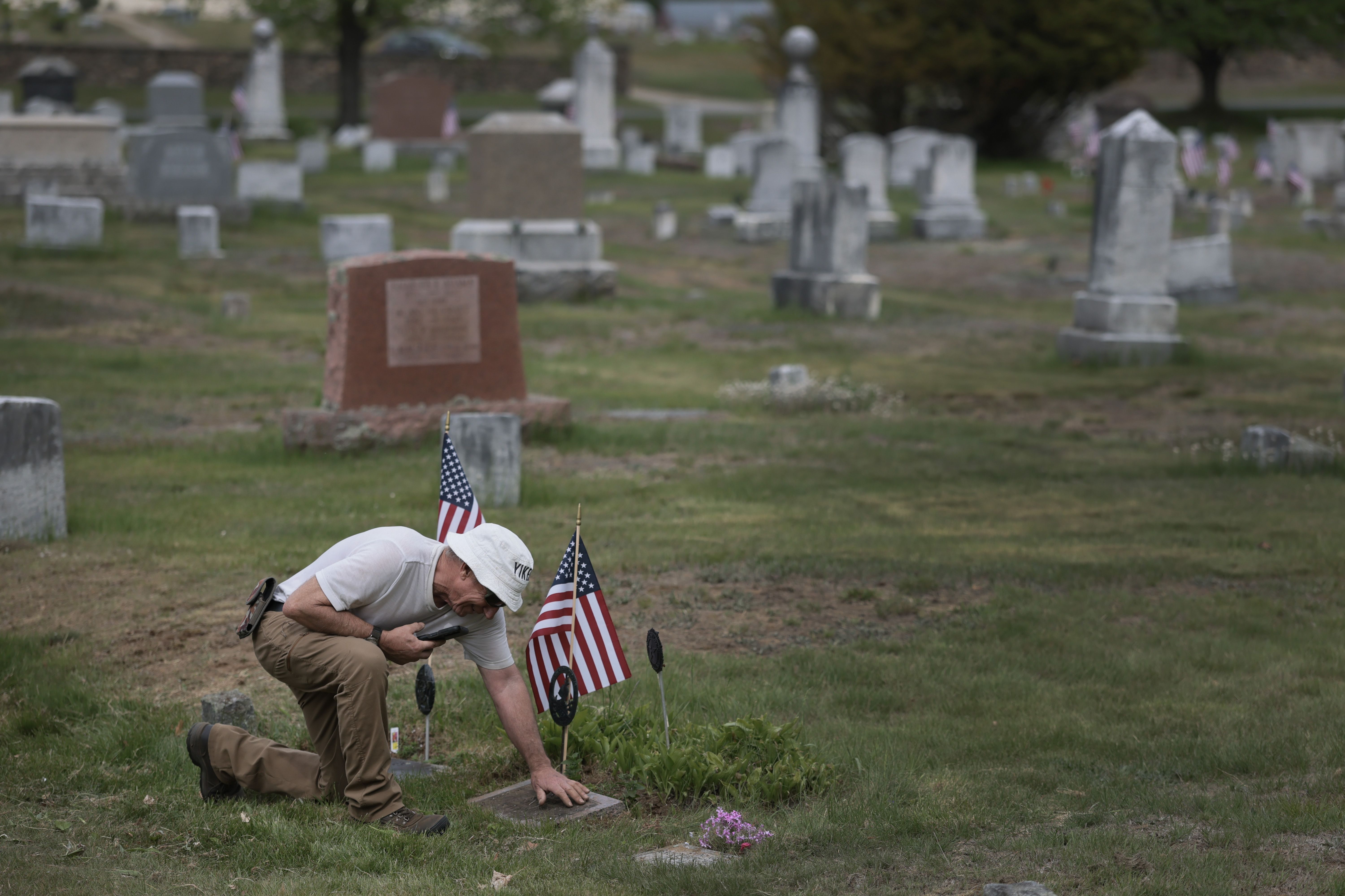 FARMINGTON, MAINE - MAY 23: Robin Hutchinson cleans off the gravestone of his grandfather, who was a WW II veteran, at the Riverside Cemetery on May 23, 2026 in Portland, Maine. Hutchinson said he visits the grave every Memorial Day weekend. Memorial Day weekend marks the unofficial start of summer