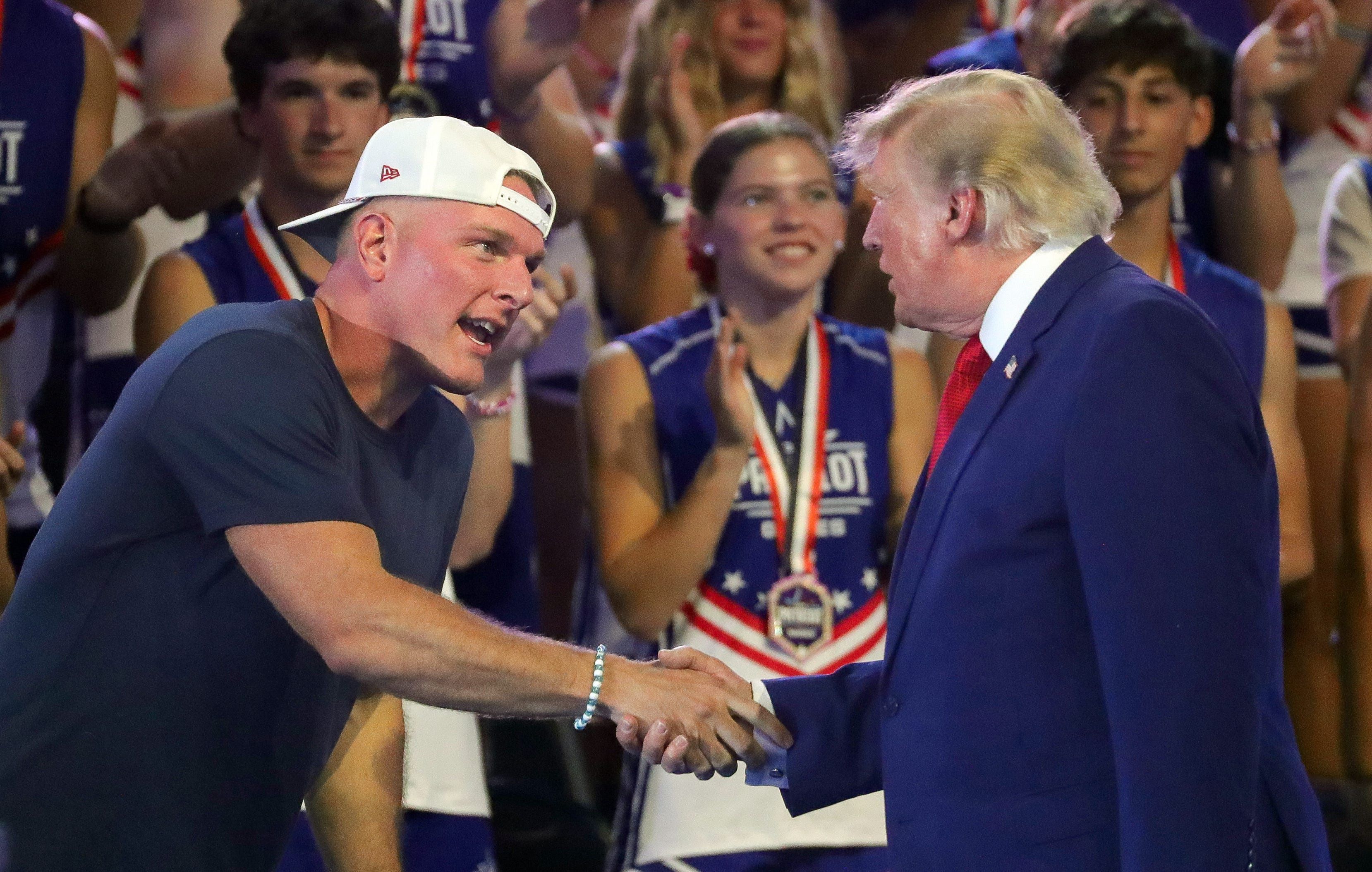 ESPN host Pat McAfee greets President Trump yesterday during Freedom 250's Patriot Games Finale at Spire Academy in Geneva, Ohio. Photo: Jeff Lange/Akron Beacon Journal via Reuters