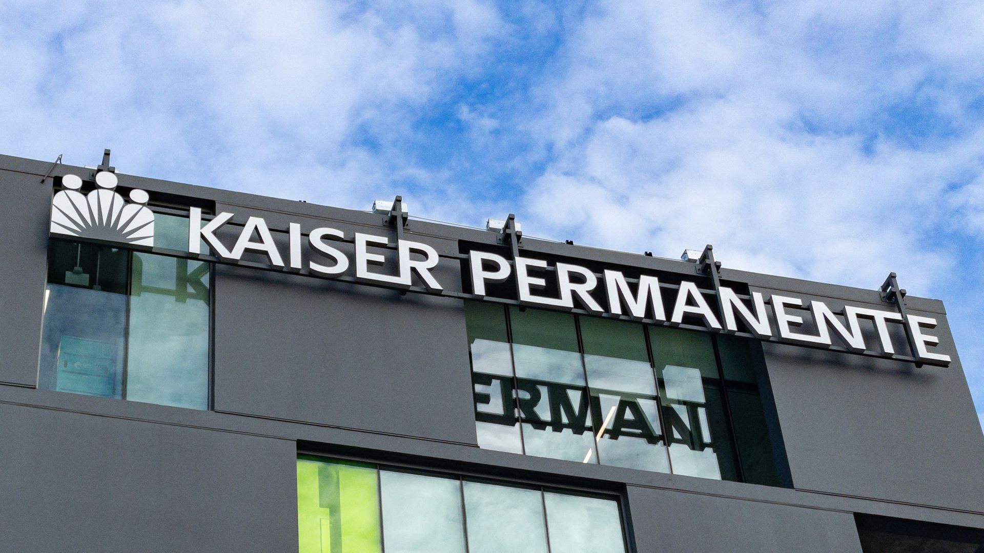 A white Kaiser Permanente logo on top of a gray medical office building.