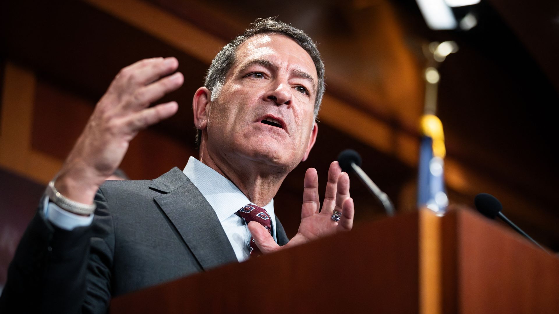 House Homeland Security Committee Chair Mark Green, wearing a gray suit and holding up his hands behind a wooden podium.