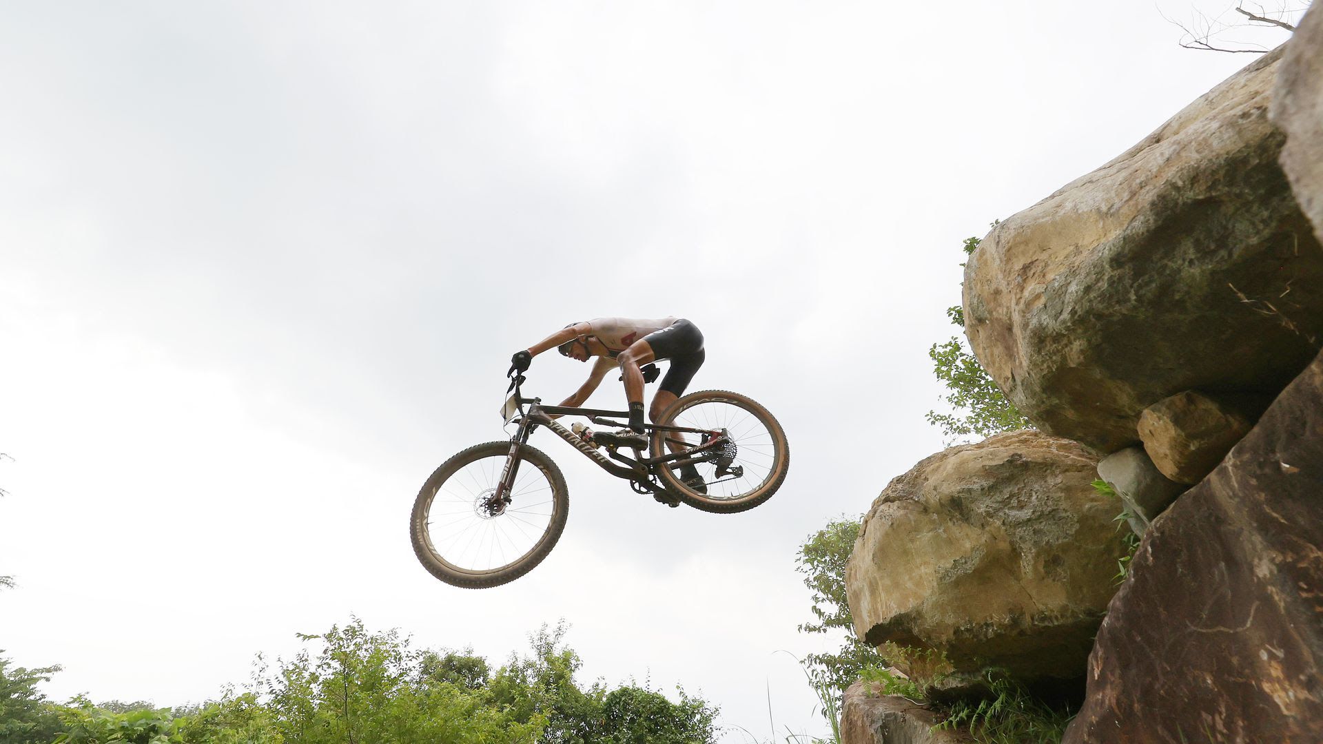 A mountain biker jumps in the air off rocks.