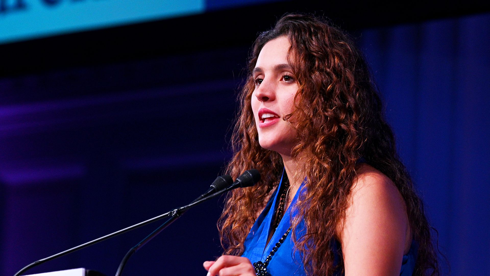 Brisa De Angulo speaks in front of a microphone