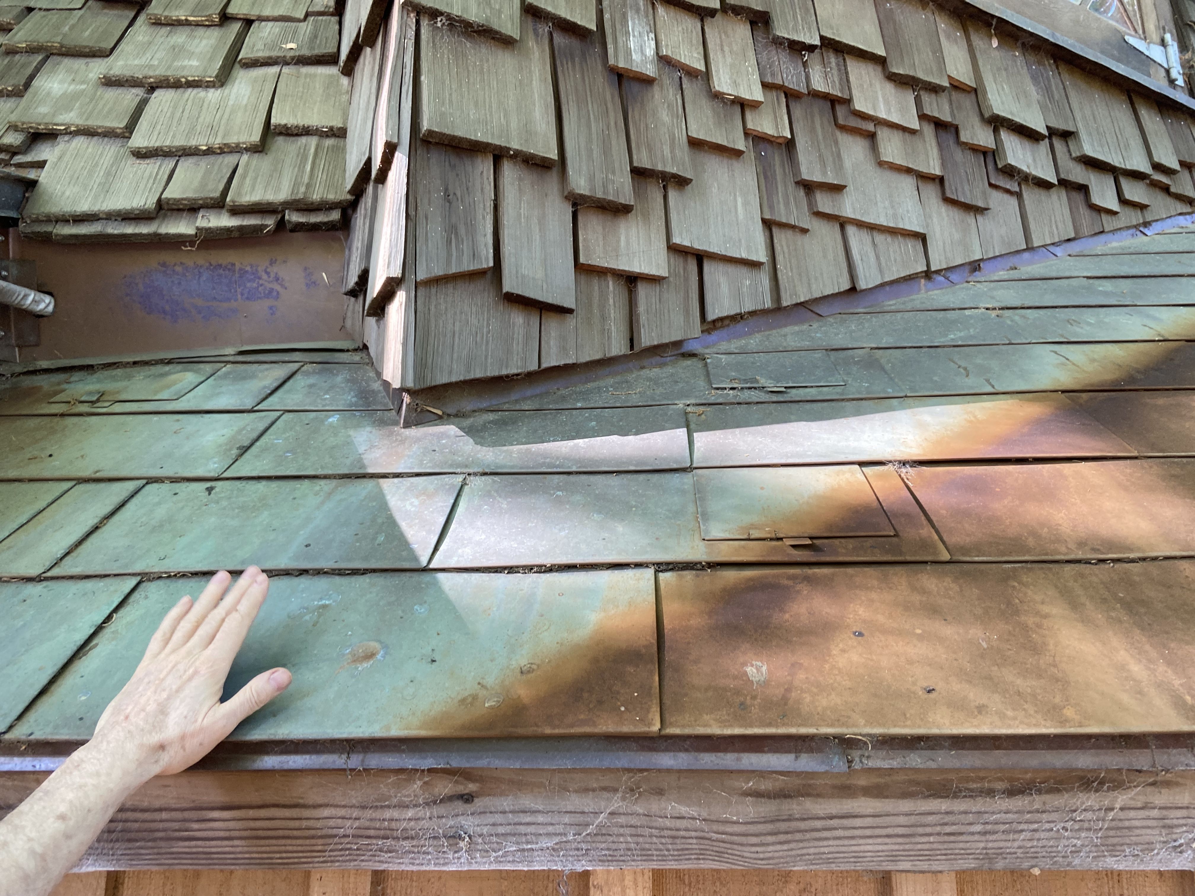 A photo of a man showing the contrast on copper shingles after they’ve been exposed to the elements