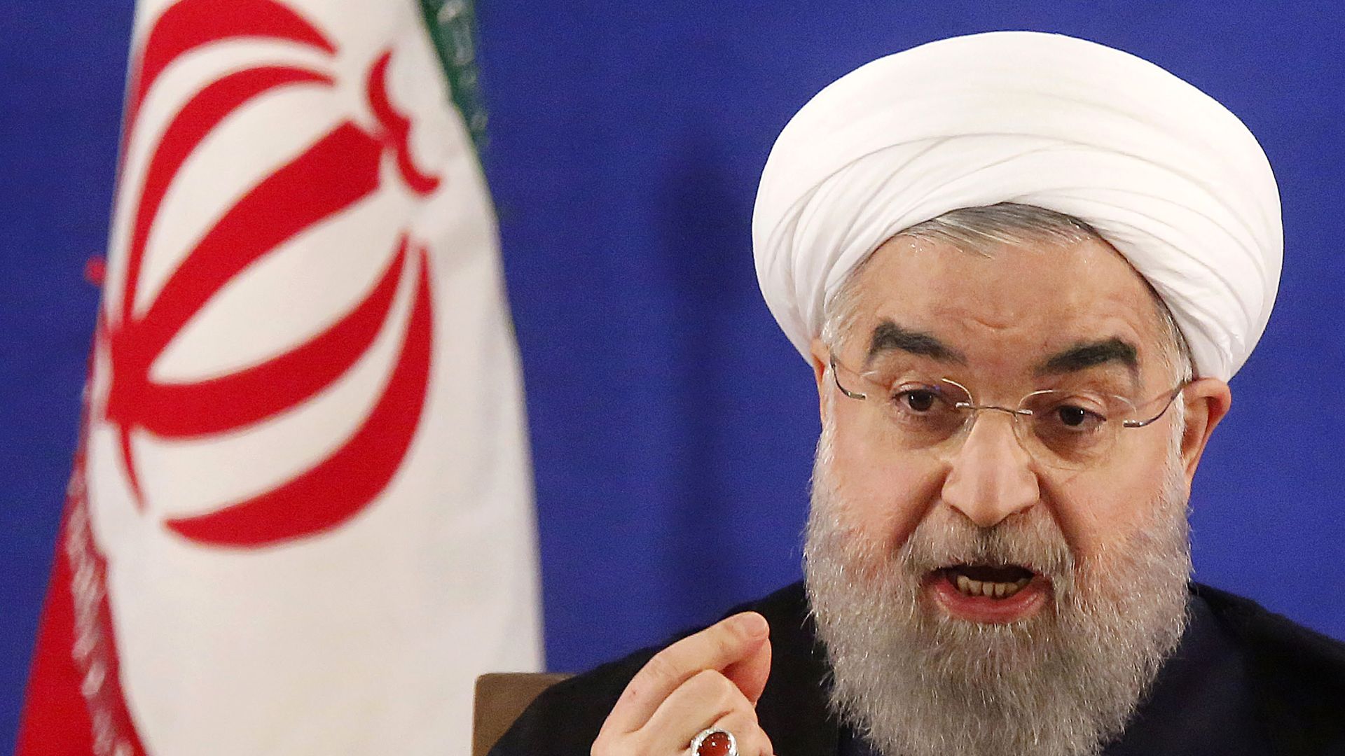 Iranian President Rouhani speaking at a podium, gesturing sternly