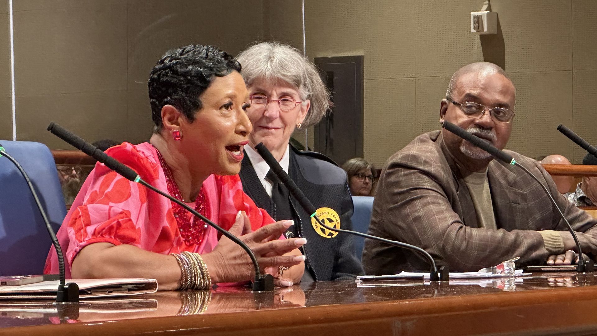 Photo shows Michelle Woodfork speaking into a microphone while Anne Kirkpatrick and Norman Robinson look on.